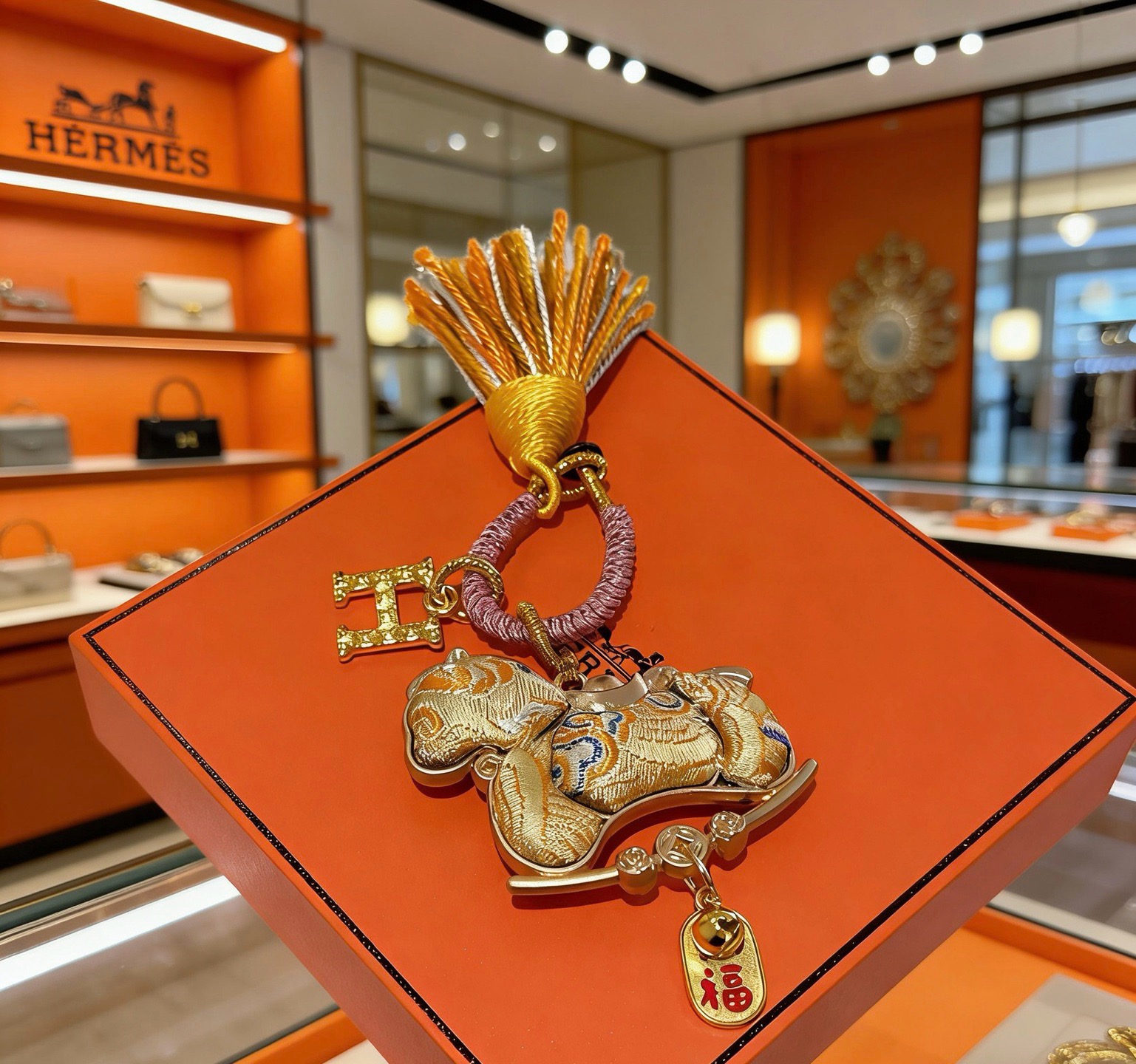 Pendentif porte-clés avec breloque cheval du Nouvel An chinois Hermes Métal doré Cordon tressé rose doré et pompon orange et blanc Tissu doré avec broderie bleue Breloque texte en émail rouge Longueur totale 12 cm