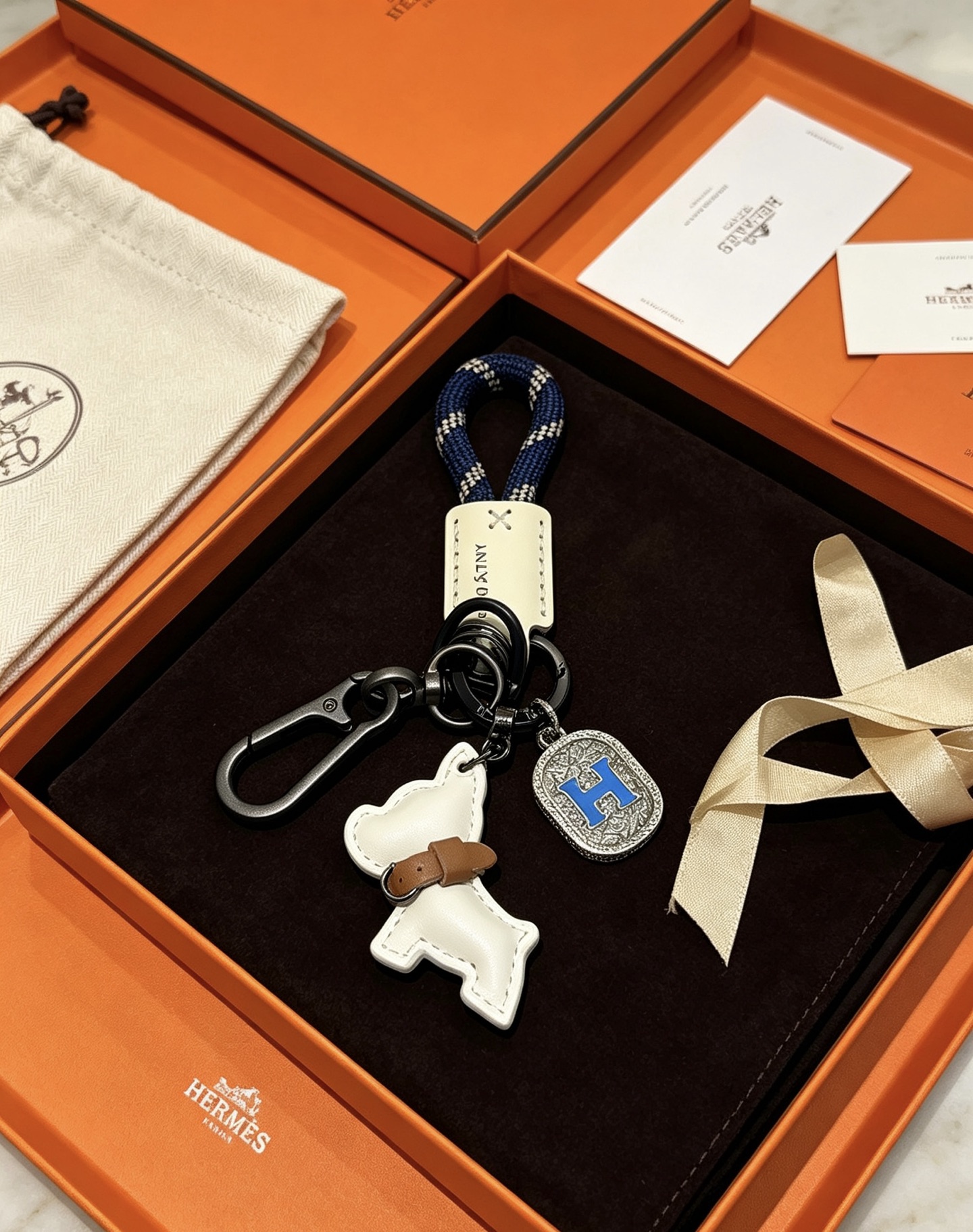 Hermes H Logo Puppy Charm Porte-clés pendentif Gunmetal matériel noir corde tressée bleu marine cuir blanc cassé cuir beige émail bleu Breloque H breloque gravée argentée 12 cm de longueur totale