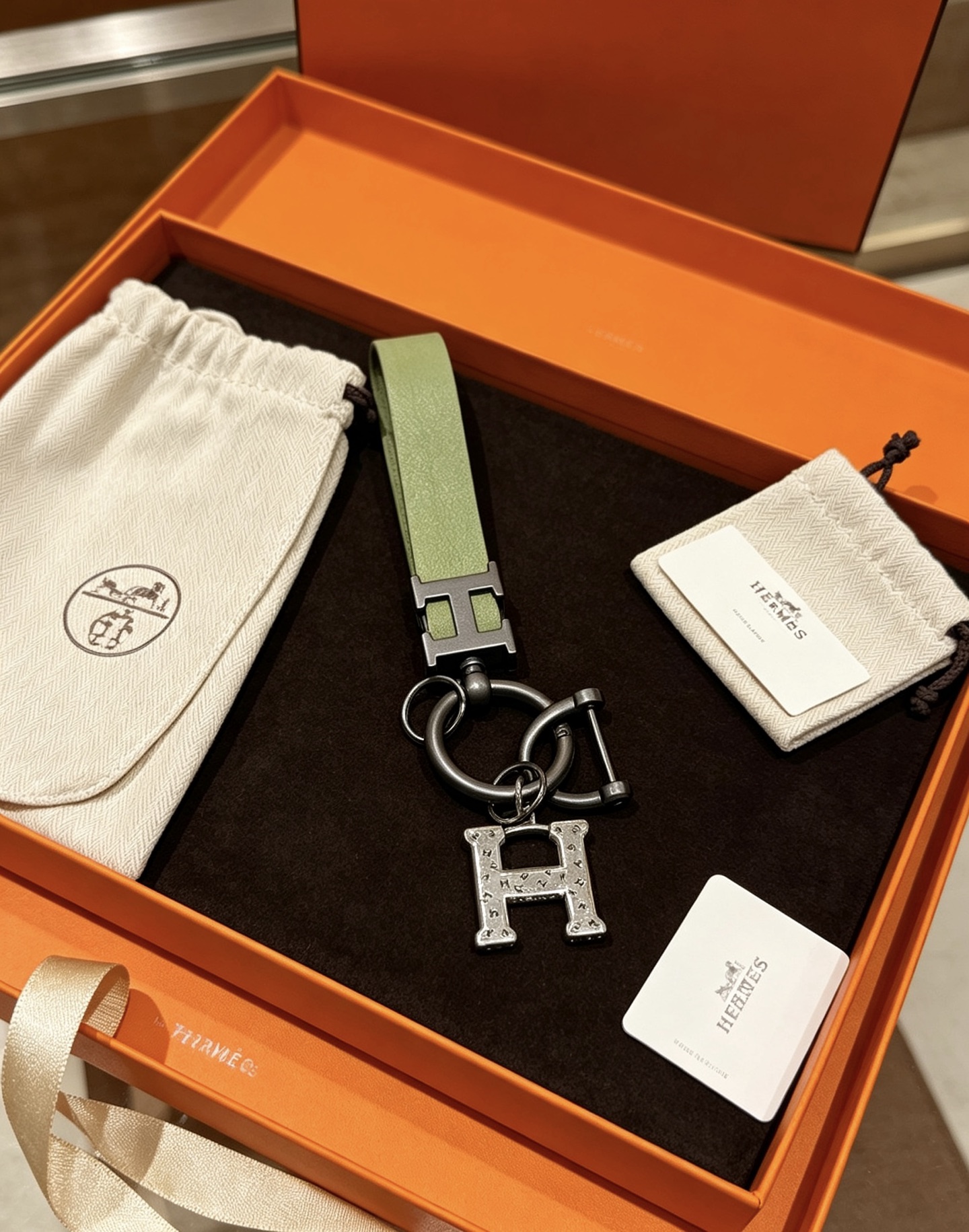 Hermes H Logo Leather Strap Keychain pendant Light green leather strap gunmetal gray metal hardware brushed silver H charm 12cm total length