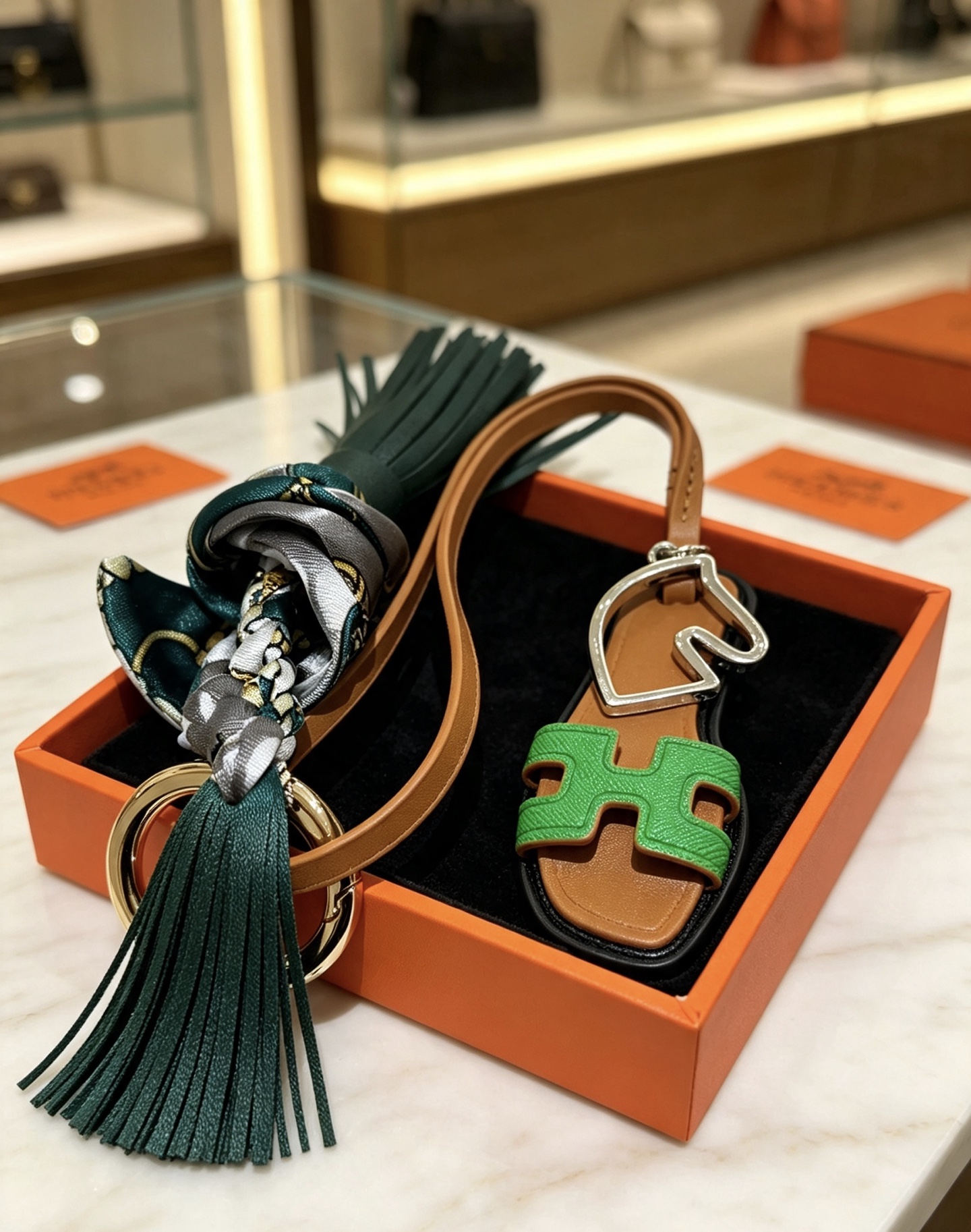 Hermes Oran Sandal Tassel Silk Twilly Bag Charm Keychain pendant Gold-tone and silver-tone metal brown leather dark green leather tassel green Epsom leather H detail multicolor gray-green-gold silk twilly 17cm strap length