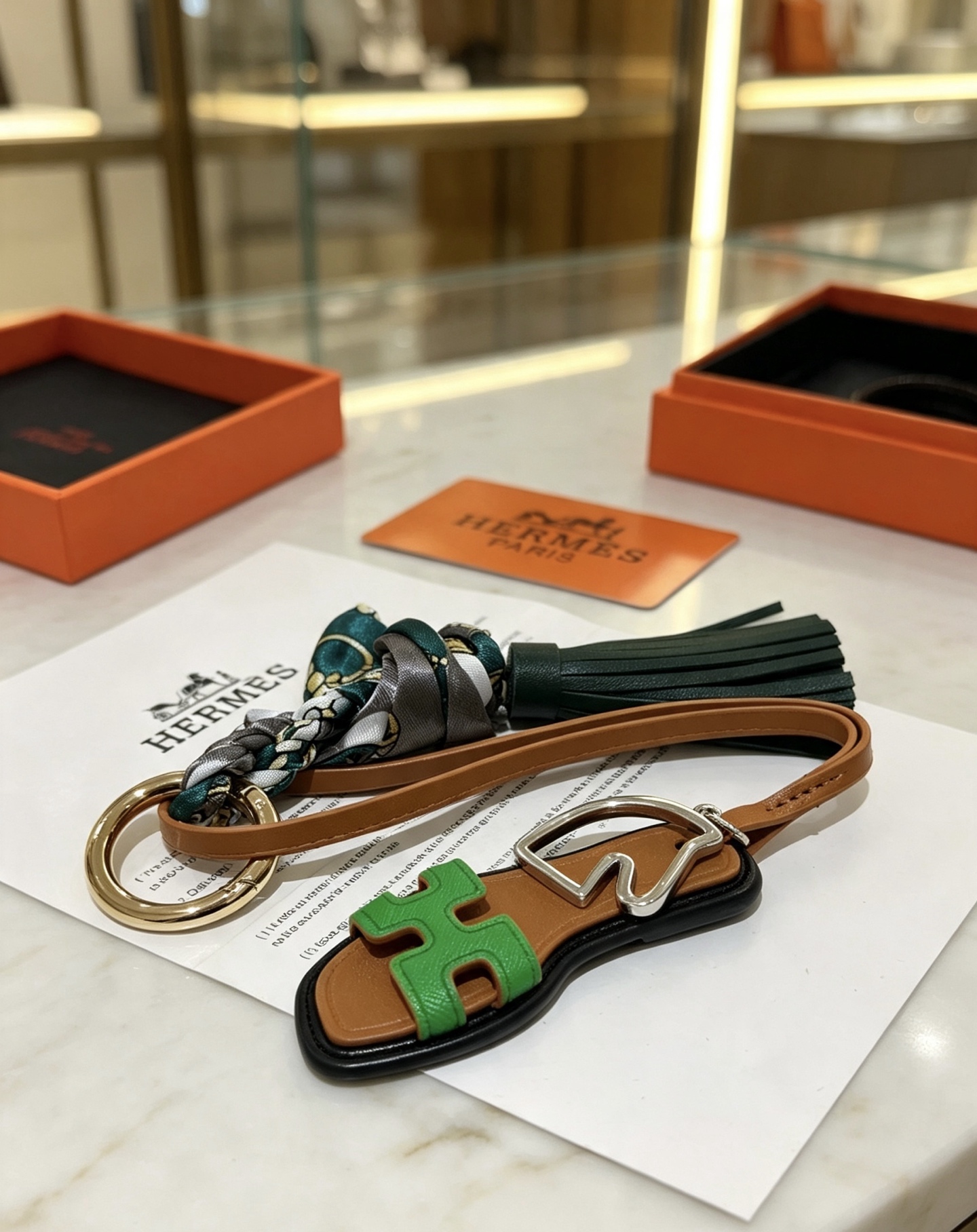 Hermes Oran Sandal Tassel Silk Twilly Bag Charm Keychain pendant Gold-tone and silver-tone metal brown leather dark green leather tassel green Epsom leather H detail multicolor gray-green-gold silk twilly 17cm strap length