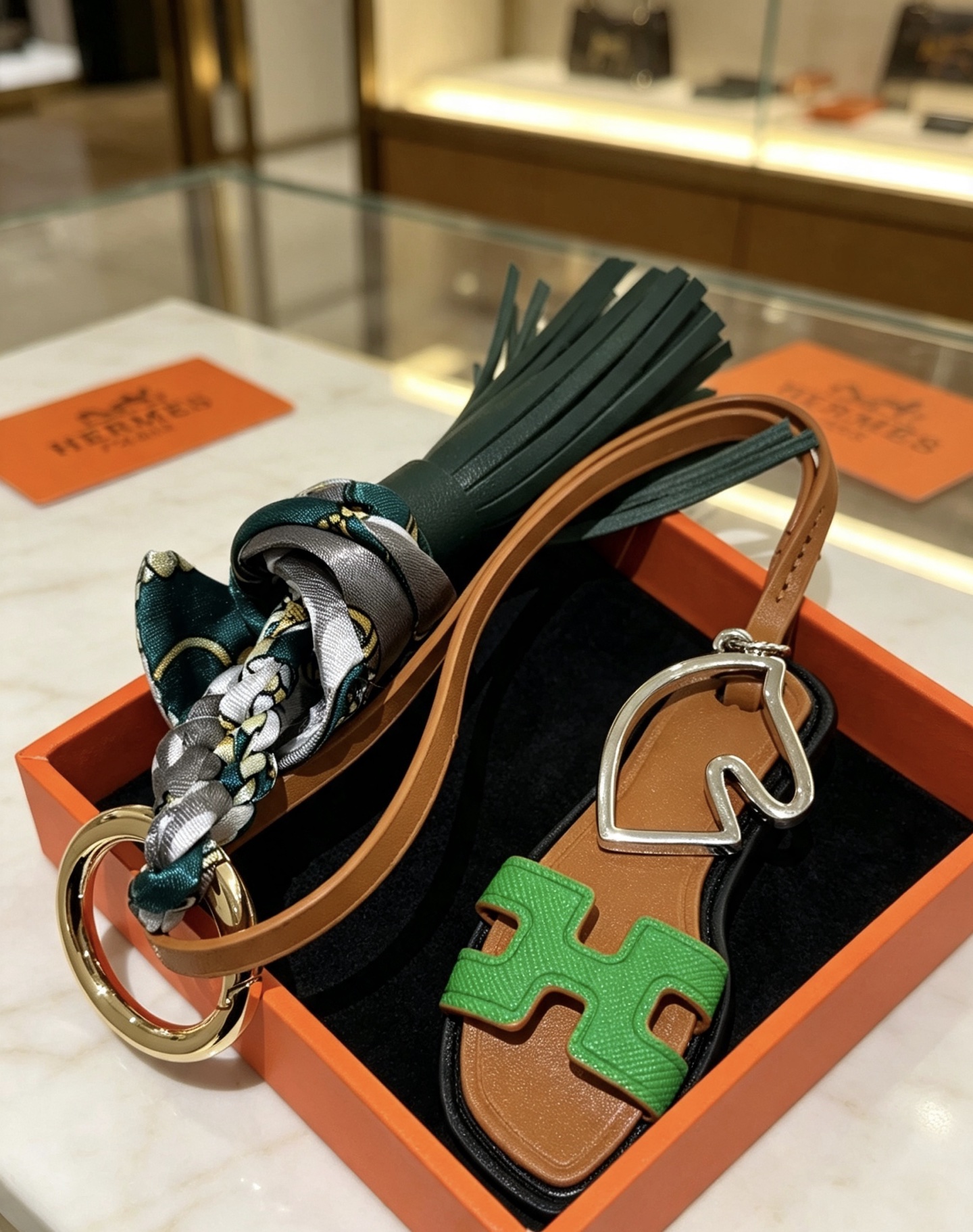 Hermes Oran Sandal Tassel Silk Twilly Bag Charm Keychain pendant Gold-tone and silver-tone metal brown leather dark green leather tassel green Epsom leather H detail multicolor gray-green-gold silk twilly 17cm strap length
