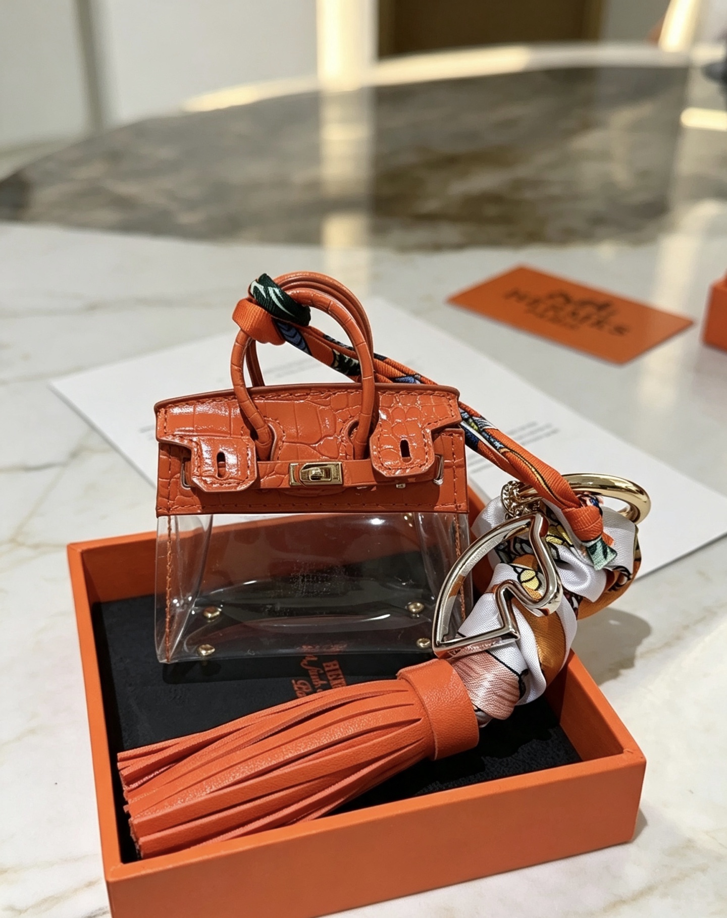 Borsa Hermes Mini Birkin Nappa Ciondolo ciondolo Pelle arancione goffrata coccodrillo PVC trasparente metallo color oro nappa in pelle arancione seta stampata multicolore Lunghezza totale 12 cm