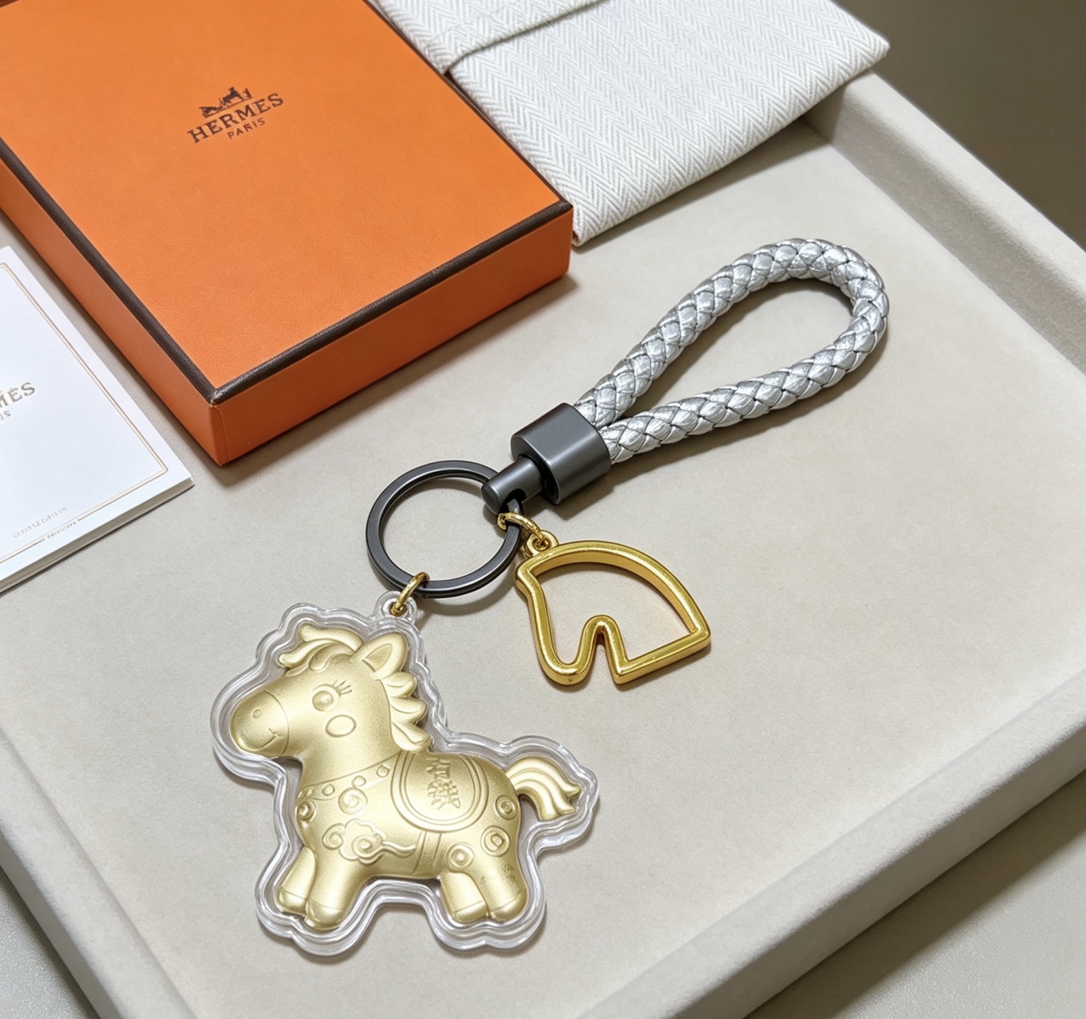 Hermes Cheval Horse Charm Porte-clés pendentif Breloque cheval en or mat accent de tête de cheval doré bracelet en cuir tressé argenté matériel noir en bronze à canon couvercle de charme de protection transparent 12 cm poignet tressé