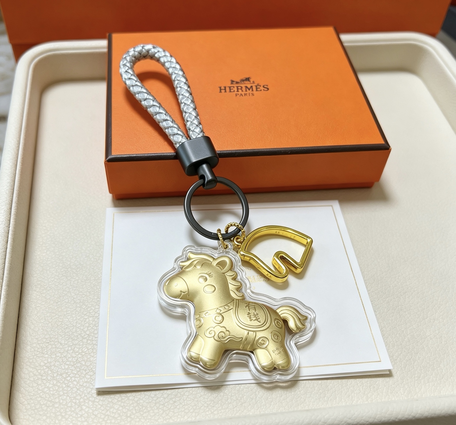 Hermes Cheval Horse Charm Porte-clés pendentif Breloque cheval en or mat accent de tête de cheval doré bracelet en cuir tressé argenté matériel noir en bronze à canon couvercle de charme de protection transparent 12 cm poignet tressé