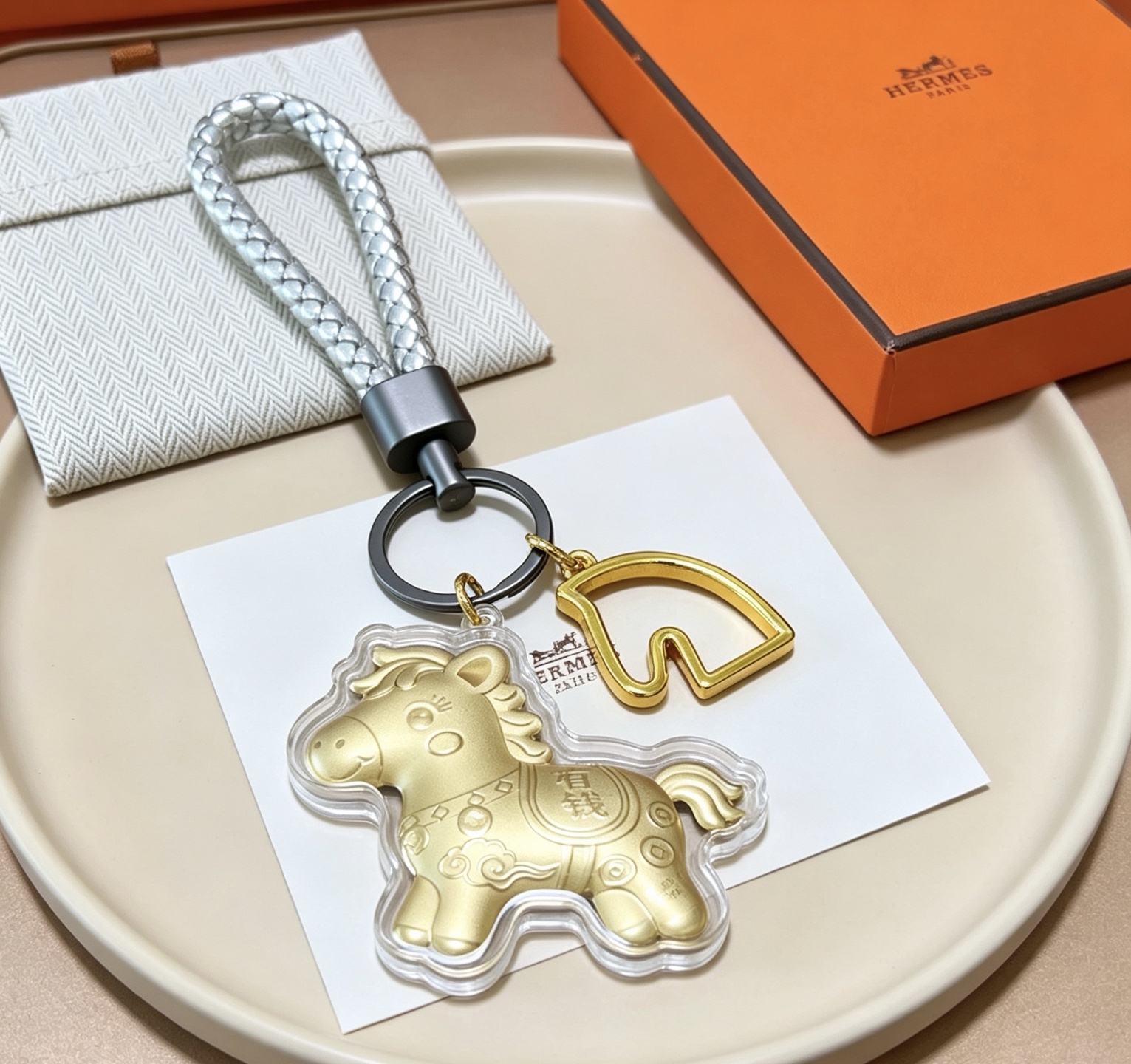 Hermes Cheval Horse Charm Porte-clés pendentif Breloque cheval en or mat accent de tête de cheval doré bracelet en cuir tressé argenté matériel noir en bronze à canon couvercle de charme de protection transparent 12 cm poignet tressé