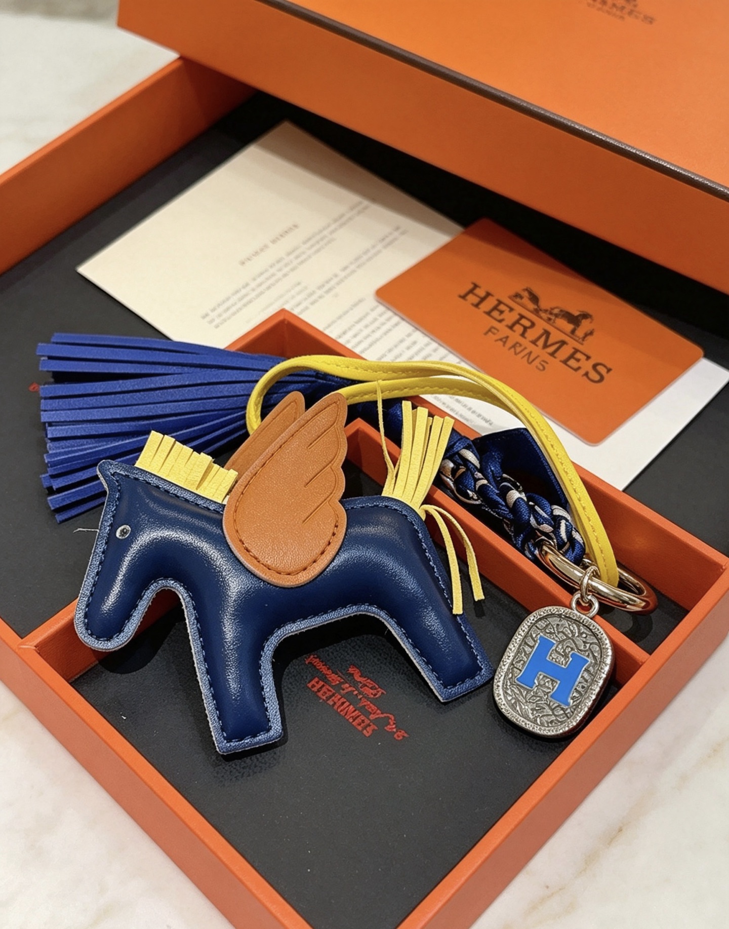 Hermes Rodeo Pegase H Logo Charm pendant Navy blue leather body tan leather wings yellow leather straps and mane bright blue leather tassels silver-tone metal with blue enamel H charm 10cm