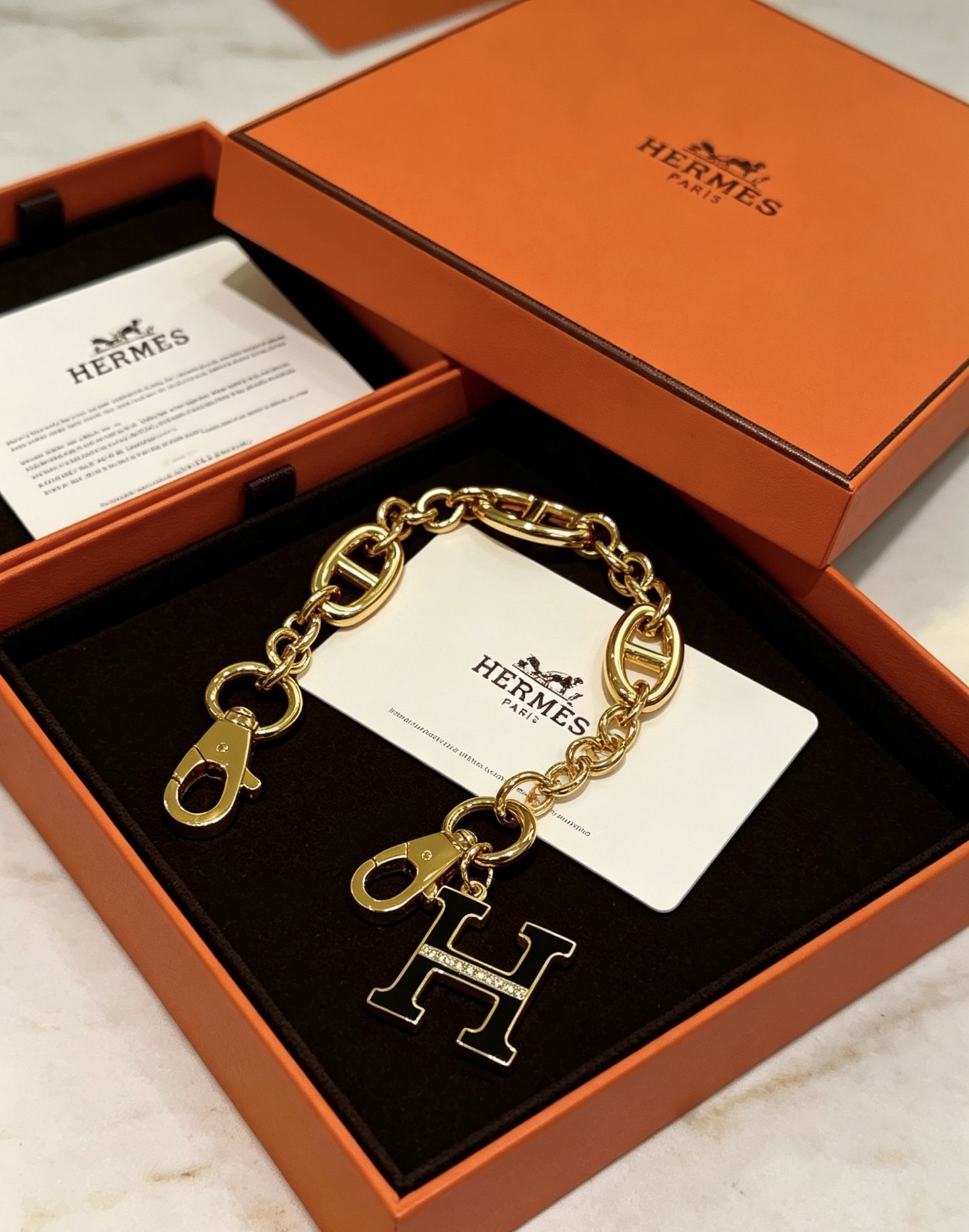 Hermes H Logo Chaine d Ancre Bag Charm Porte-clés pendentif Métal doré avec émail noir et accents de cristaux transparents 16 cm