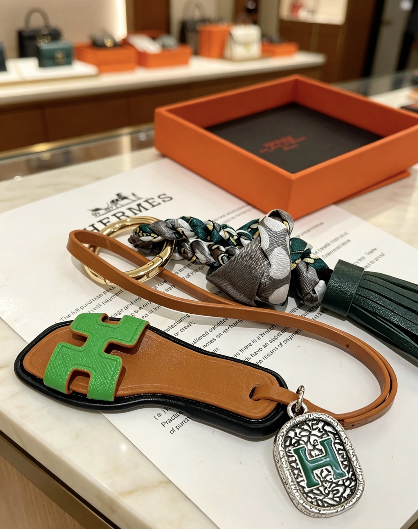 Hermes Oran Sandália Tassel Bag Pingente com pingente de metal dourado couro bronzeado couro verde brilhante couro verde escuro cinza bolinhas seda metal prateado com esmalte verde Detalhe H 12 cm de comprimento total