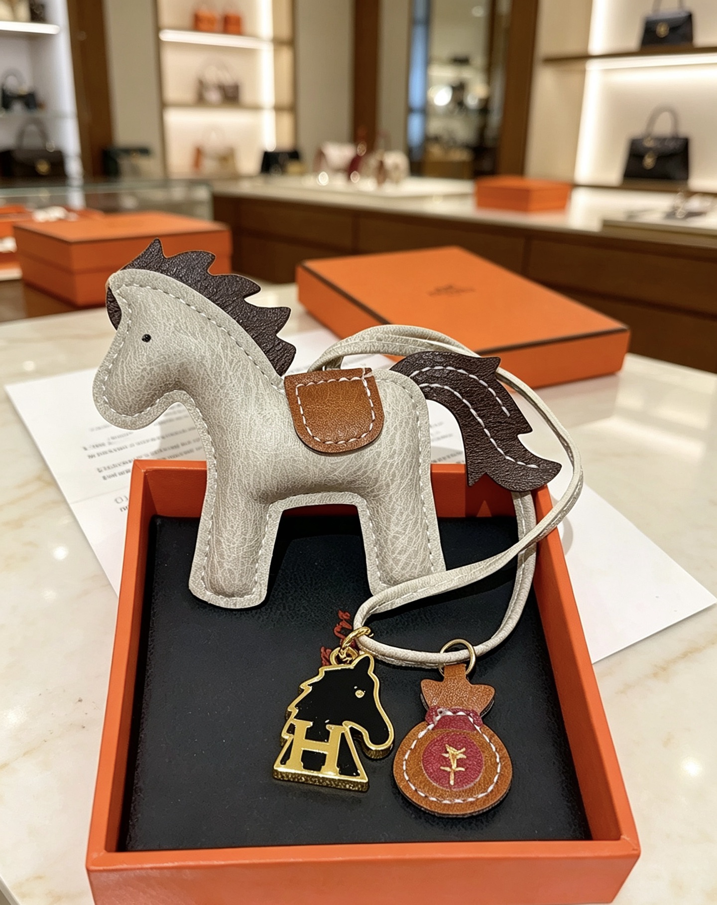 Hermes Rodeo Pegase Horse Bag Charm pendant Light gray grained leather with dark brown leather mane tail tan leather saddle gold-tone metal hardware black enamel H horse charm burgundy leather money bag charm 8cm charm with 12cm leather strap