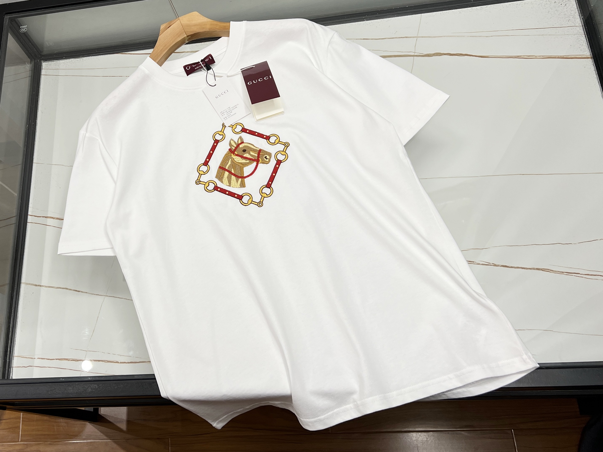 NO:676704,-26SS————The fusion of fashion and culture in the middle embroidered horse short sleeves. This middle embroidered horse short sleeves is undoubtedly a unique existence in the fashion world. The overall style of the short sleeves is simple and elegant, and the smooth lines outline a neat outline, making it comfortable and energetic to wear.  The most eye-catching thing is undoubtedly the lifelike embroidered horse in the center. The stitching is exquisite and exquisite, and every thread seems to be given life, perfectly presenting the horse's strong posture and flying mane, as if it is about to gallop out in the next second.  The horse symbolizes vitality, progress and success in Chinese culture. Wearing it not only adds a different oriental charm to daily wear, but also seems to bring a positive spiritual power. Whether you wear it with casual pants for walking on the street or with jeans for a party, it can make you stand out from the crowd and become the focus. Available in stock in two colors S-XL, Gucci-clothing, gucci, jeans, T-shirt,19860909-26SS———中间刺绣马短袖时尚与文化的交融 这件中间刺绣马短袖,无疑是时尚界的独特存在.短袖整体版型简约大方,流畅的线条勾勒出利落的轮廓,穿着舒适又显精神. 其最吸睛之处,当属正中央那匹栩栩如生的刺绣骏马.针法细腻精湛,每一根丝线都仿佛被赋予了生命,将马的矫健身姿、飞扬鬃毛完美呈现,仿佛下一秒就要奔腾而出. 马在中国文化里象征着活力、进取与成功,穿上它,不仅为日常穿搭增添了一抹别样的东方韵味,更似带着一份积极向上的精神力量.无论是搭配休闲裤漫步街头,还是配牛仔裤参加聚会,它都能让你在人群中脱颖而出,成为焦点. 现货发售二色S-XL,古驰-服装,gucci,jeans,T-shirt,,Women's clothing