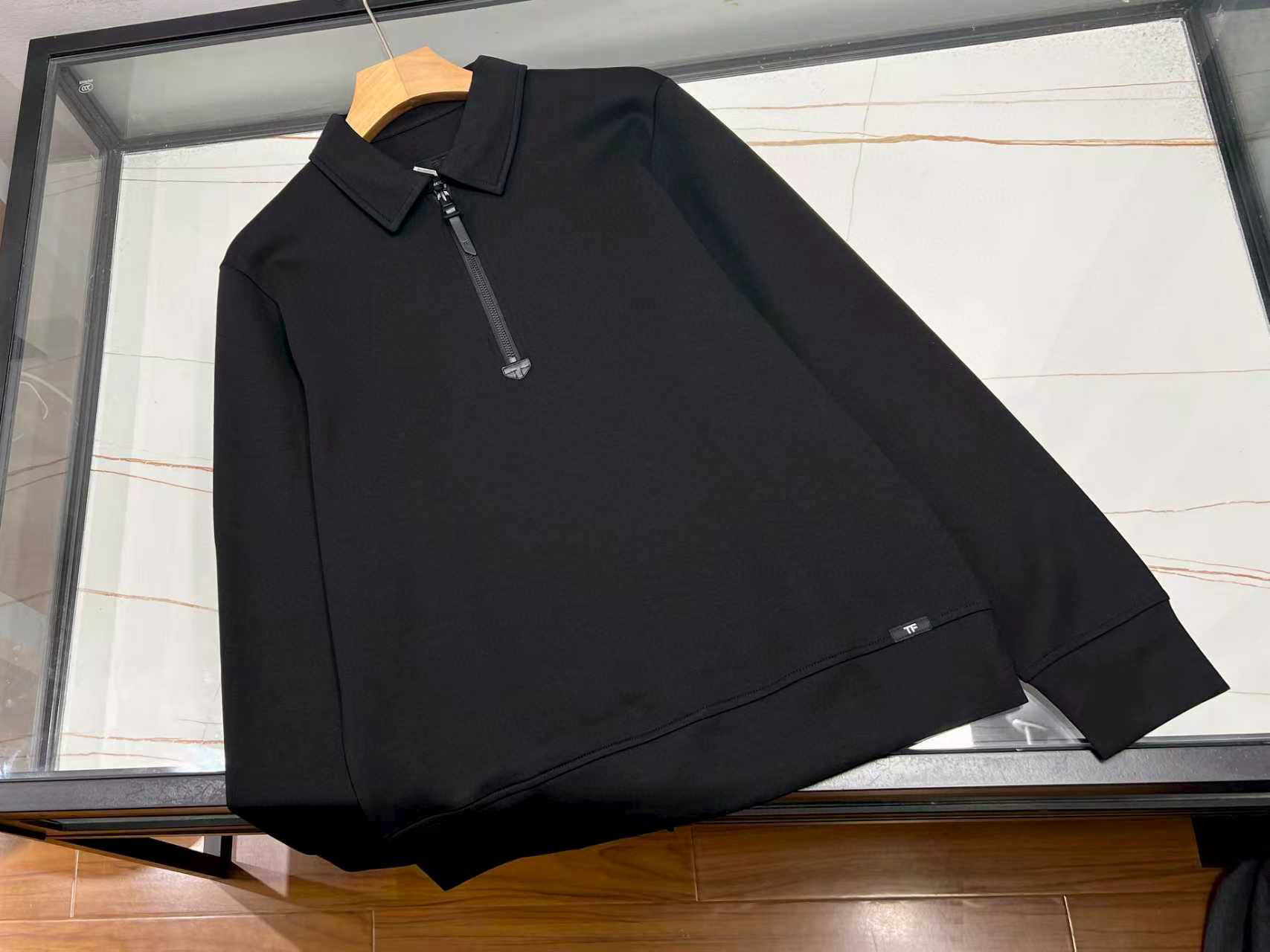 NO:714337,——TF semi-open lapel sweatshirt, based on classic black, blends high-quality fabrics and exquisite craftsmanship to create a daily item that combines comfort and style.  The fabric is made of modal air layer, which is scientifically mixed with 40.3 modal, 38.6 cotton, 15 polyester fiber and 6.1 spandex. The softness and fineness of modal complement the natural skin-friendly feeling of cotton, giving the fabric a soft and waxy touch like a cloud; the polyester fiber enhances the stiffness and combines with the micro-elastic properties of spandex to ensure that you can freely stretch the space when wearing it, while maintaining the drape and shape of the clothes, and will not be easily deformed after long-term wear.  The design continues the brand's simple aesthetics with a half-open zipper layout. You can easily adjust the wearing status between opening and closing to suit the needs of different occasions. The zipper puller is decorated with TF's iconic leather tab. The warm texture of the leather forms a clever contrast with the metal zipper, low-key highlighting the brand recognition. Lapel  The cut is neat and smooth, outlining the simple neck line, giving it a casual and decent feel. The hem and cuffs are made of the same fine threaded edge, which naturally connects with the air-layer fabric of the body, which not only enhances the fit of the wearer, but also avoids loose curling, and the details are exquisite.  Whether paired with suit pants for daily commuting or jeans for casual occasions, this black shirt can become a versatile choice in the wardrobe with both practicality and taste due to its calm tone and comfortable experience. Available now in black 48-56, men's clothing, tom ford, jeans, business suit,19860909——TF半开襟翻领球衫,以经典黑色为基底,融萃优质面料与精湛工艺,塑造兼具舒适与格调的日常单品.  面料选用莫代尔空气层,由40.3莫代尔、38.6棉、15聚酯纤维及6.1氨纶科学配比而成.莫代尔的柔软细腻与棉的天然亲肤相得益彰,赋予面料如云朵般的软糯触感；聚酯纤维增强挺括度,配合氨纶的微弹特性,确保穿着时既有自在舒展的活动空间,又能保持衣物的垂坠有型,久穿不易变形.  设计上延续品牌简约美学半开襟拉链布局,开合间从容调节穿着状态,适配不同场合需求；拉链头缀以TF标志性皮袢,皮革的温润质感与金属拉链形成巧妙对比,低调彰显品牌辨识度.翻领剪裁利落流畅,勾勒出简洁颈部线条,兼具休闲与得体感.下摆与袖口均采用同面料的细腻螺纹收边,与大身空气层面料自然衔接,既强化穿着的贴合度,又避免卷边松垮,细节处尽显精致.  无论是日常通勤搭配西装裤,还是休闲场合配搭牛仔裤,这件黑色球衫都能以其沉稳色调与舒适体验,成为衣橱中兼具实用性与品味的百搭之选. 现货发售黑色48-56,男装,tom ford,jeans,business suit,,Women's clothing