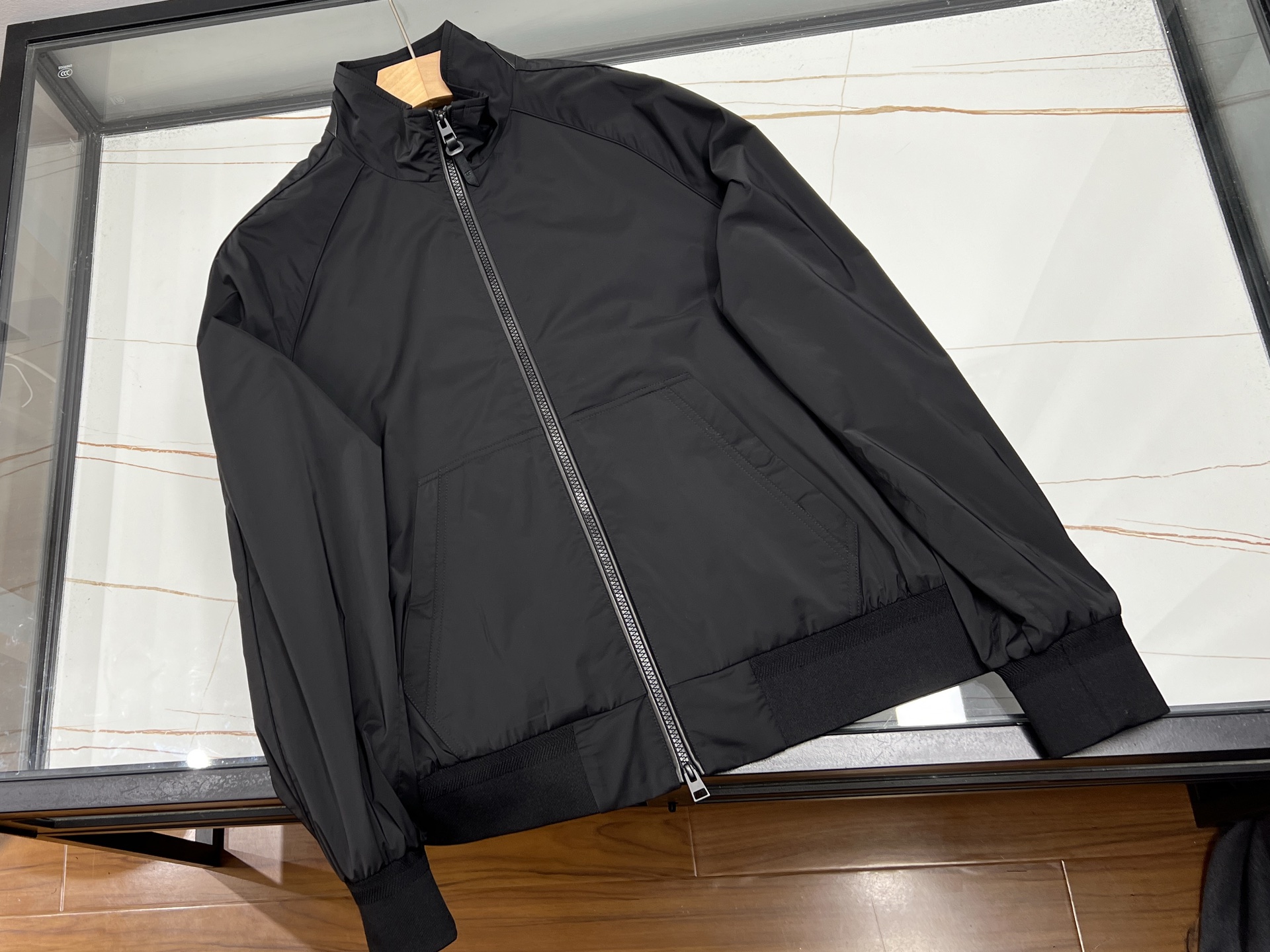 NO:722345,-26SS———— Product introduction of TF Solona three-proof stand-up collar jacket. This TF stand-up collar jacket is designed with 'triple black texture' and matched with polyester fiber Solona three-proof fabric, making it a light sports item with both function and style in spring and summer. Fabric performance The outer layer of Solona three-proof fabric is windproof, waterproof and stain-proof, and relies on fiber characteristics to remain breathable and light, adapting to the warm environment and changeable weather in spring and summer.  The design details adopt the 'triple black tone' texture collision - matte black of the fabric, delicate black of the leather piping, and transparent black of the resin zipper and puller. The black levels of the three materials are distinct but harmonious, showing high-end simplicity; the piping seams of the raglan sleeves ensure freedom of movement, and the double-open zipper opening and closing is flexible and lightweight; the patch pocket design has a sense of movement and relaxation, and the hem and cuffs are threaded to enhance wind protection. The leather patchwork on the back collar and leather collar tabs reveal exquisite details.  Wearing scene: T-shirt and casual pants for morning commuting. It is neat and easy to cope with light outdoor travel with protective performance. It is the core choice of spring and summer wardrobe with both function and style. Available in stock, black 48-56, men's clothing, tom ford, jackets & coats, tees, t-shirt,19860909-26SS———TF索罗娜三防立领夹克产品介绍 这款TF立领夹克,以“三重黑调质感”为设计巧思,搭配聚酯纤维索罗娜三防面料,成为春夏兼具功能与格调的轻运动单品. 面料性能外层索罗娜三防面料,实现防风、防水、防污的同时,依托纤维特性保持透气轻盈,适配春夏温热环境与多变天气. 设计细节采用“三重黑调”质感碰撞——面料的哑光黑、皮革滚边的细腻黑、树脂拉链及拉头的通透黑,三种材质的黑色层次分明却和谐统一,尽显高级简约；插肩袖滚边拼缝保障活动自由度,双开拉链开合灵活且轻量化；贴袋设计自带运动松弛感,下摆与袖口螺纹收边强化防风,后领拼皮与皮质领袢则在细节处流露精致. 穿着场景晨间通勤搭T恤休闲裤显利落,轻户外出行靠防护性能从容应对,是春夏衣橱中功能与风格兼具的核心之选. 现货发售黑色48-56,男装,tom ford,jackets & coats,tees，t-shirt,,Women's clothing