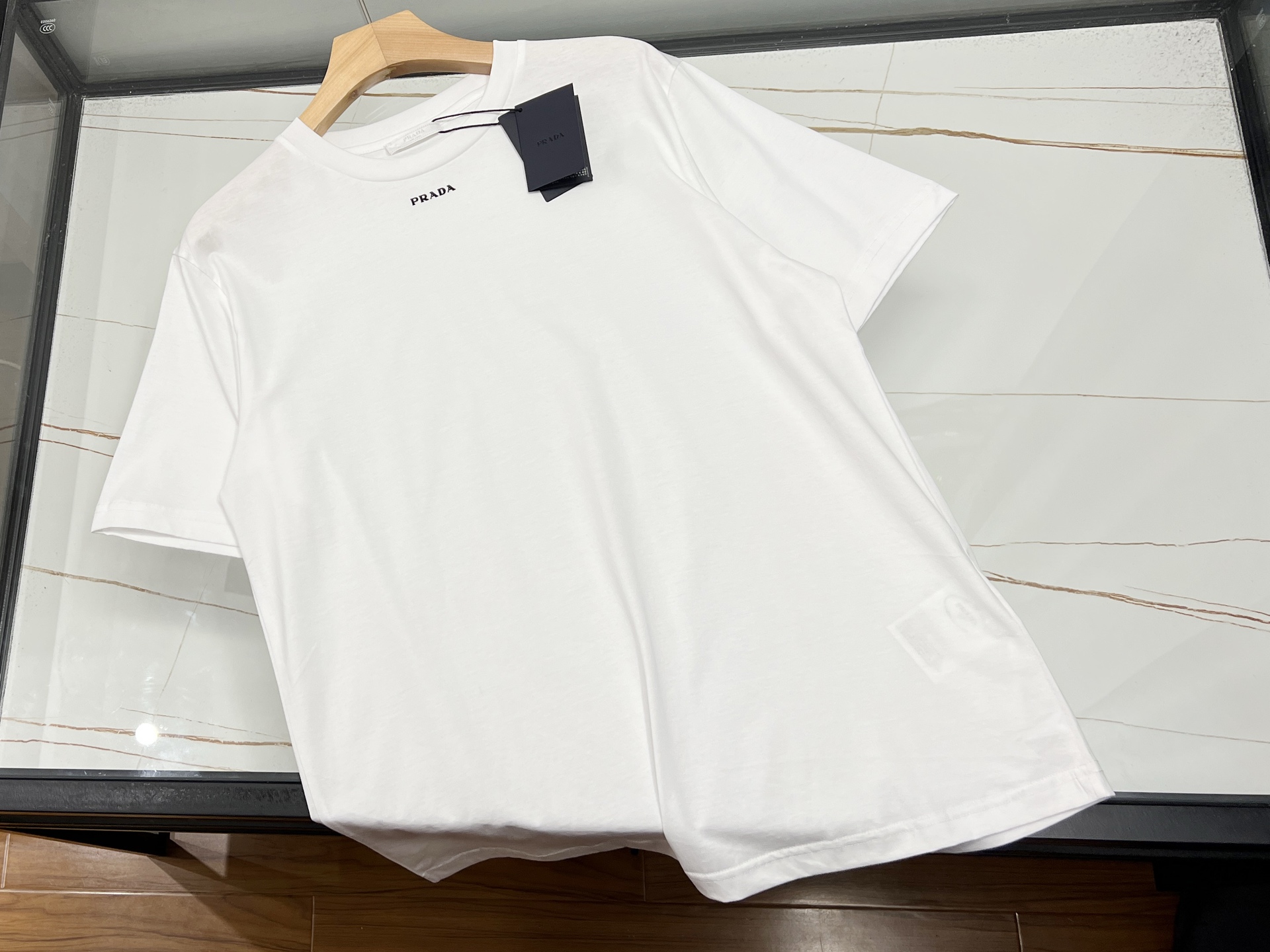 NO:775755,-26SS————Fashionable classic casual short-sleeved short-sleeved summer wardrobe plays the role of C. When the sun shines through the clouds, short-sleeved clothes become the most tacit summer dressing partner. It uses light tailoring to free up the arms, allowing every time you raise your hands to carry the freedom of the wind; it adapts to different scenes with a variety of styles, from morning commute to midnight party, it is always easy to handle.  The classic round-neck short-sleeve is the 'Taiwan Balm' in the wardrobe. The pure cotton fabric is skin-friendly and breathable, as if being embraced by clouds. Its sweat-absorbing and quick-drying properties instantly dissipate the sticky feeling under high temperatures. If you want to lengthen the neck line, your elegance will naturally appear. The printed short-sleeve is an extension of street art. Cartoon patterns awaken childlike innocence, and graffiti elements highlight your personality. Every step follows the beat of the trend.  Black and white are the eternal safety cards - black is cool and stylish, white is as refreshing as a spring. Whether paired with bright-colored bottoms or single items of the same color, they can be easily controlled. Black/white S-XL, Prada-clothing, prada, T-shirt, available for sale now.19860909-26SS————时尚经典休闲短袖夏日衣橱的C位担当 当阳光穿透云层洒下,短袖便成了夏日最默契的穿搭伙伴.它用轻盈的剪裁解放双臂,让每一次抬手都带着风的自由；以百变的风格适配不同场景,从晨间通勤到午夜派对,始终游刃有余. 经典圆领短袖是衣橱里的“万金油”,纯棉面料亲肤透气,仿佛被云朵轻拥,吸汗速干的特性让高温下的黏腻感瞬间消散.若想拉长颈部线条,优雅气质自然流露.而印花短袖则是街头艺术的延伸,卡通图案唤醒童心,涂鸦元素彰显个性,每一步都踏着潮流的节拍. 黑白两色是永恒的安全牌——黑色酷飒有型,白色清爽如泉,无论搭配亮色下装还是同色系单品,都能轻松驾驭. 现货发售黑色/白色S-XL,普拉达-服装,prada,T-shirt,,Women's clothing