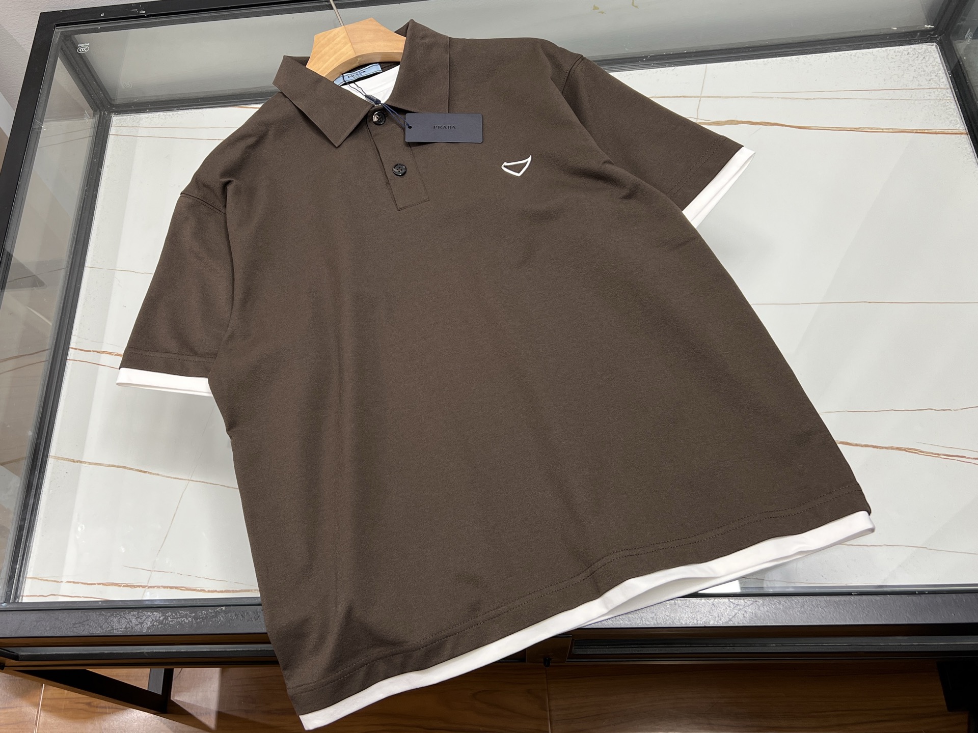 NO:785973,-26SS——Simple and fashionable, unlocking a new style of summer wear. This short-sleeved T-shirt perfectly combines simplicity and fashion. The classic lapel design is neat and spirited, easily breaking the monotony of the traditional round collar, adding a sense of sophistication and sophistication to the overall look. The unique triangle logo on the chest is the finishing touch, simple yet individual, showing your unique taste in a low-key manner, making you stand out from the crowd. The short-sleeved style is refreshing and comfortable, very suitable for hot summer wear.  The fabric is skin-friendly and breathable, comfortable and unburdened when worn close to the body, and allows you to move freely without restriction. Whether you wear it with casual pants for a stroll on the street, or with suit pants for casual business occasions, it can be easily controlled and create different styles of fashion for you. It is an indispensable and versatile item in your summer wardrobe. Available in stock, brown S-XXL, Prada-clothing, prada, T-shirt, tees, t-shirt, business suit,19860909-26SS———简约时尚,解锁夏日穿搭新风尚 这款短袖T恤,将简约与时尚完美融合.经典翻领设计,利落又精神,轻松打破传统圆领的单调感,为整体造型增添一份精致与干练. 胸前独特的三角标是点睛之笔,简约而不失个性,在低调中彰显独特品味,让你在人群中脱颖而出.短袖款式,清爽自在,非常适合炎炎夏日穿着. 面料亲肤透气,贴身穿着舒适无负担,活动自如不受限.无论是搭配休闲裤漫步街头,还是配上西装裤出席轻松商务场合,它都能轻松驾驭,为你打造出不同风格的时尚造型,是夏日衣橱里不可或缺的百搭单品. 现货发售咖啡色S-XXL,普拉达-服装,prada,T-shirt,tees，t-shirt,business suit,,Women's clothing