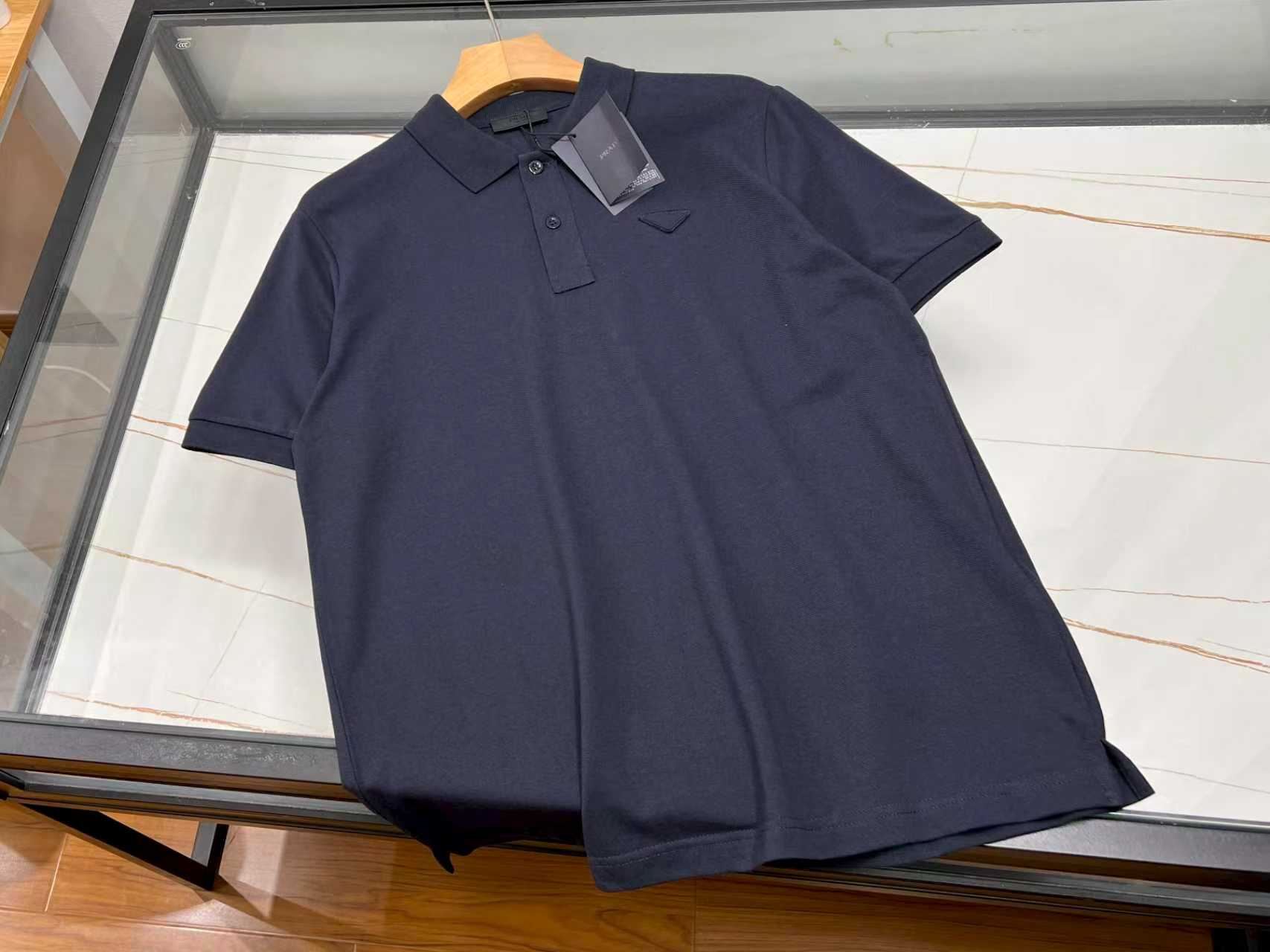 NO:820483,—26SS———P Triangle logo fashionable lapel short sleeves unlock the summer trend code. This triangle logo fashionable lapel short sleeves are an eye-catching artifact for the summer wardrobe. The classic lapel design is neat and capable, cleverly modifying the neck line, adding a sense of sophistication to the overall shape. The unique triangle logo element on the chest is individual and eye-catching, instantly breaking the monotony and highlighting unique fashion taste. The short-sleeved style is refreshing and breathable, bringing the slightest coolness in the hot summer.  The fabric is soft and skin-friendly, comfortable and comfortable to wear, and there is no sense of restraint in activities. Whether paired with casual shorts, strolling on the streets, enjoying leisure time; or paired with suit trousers, attending relaxed business occasions, it can be easily controlled, allowing you to stay fashionable and confident at all times, becoming the focus of the crowd. Available in stock in two colors S-XL, Prada-clothing, prada, shorts, T-shirt, business suit,19860909—26SS———P三角标时尚翻领短袖解锁夏日潮流密码 这款三角标时尚翻领短袖,是夏日衣橱的吸睛神器.经典翻领设计,利落又干练,巧妙修饰颈部线条,为整体造型增添一份精致感. 胸前独特的三角标元素,个性又吸睛,瞬间打破单调,彰显独特时尚品味.短袖款式,清爽透气,在炎炎夏日带来丝丝凉意. 面料柔软亲肤,穿着舒适自在,活动毫无束缚感.无论是搭配休闲短裤,漫步在街头,享受悠闲时光；还是配上西装长裤,出席轻松的商务场合,它都能轻松驾驭,让你时刻保持时尚与自信,成为人群中的焦点. 现货发售二色S-XL,普拉达-服装,prada,shorts,T-shirt,business suit,,Women's clothing