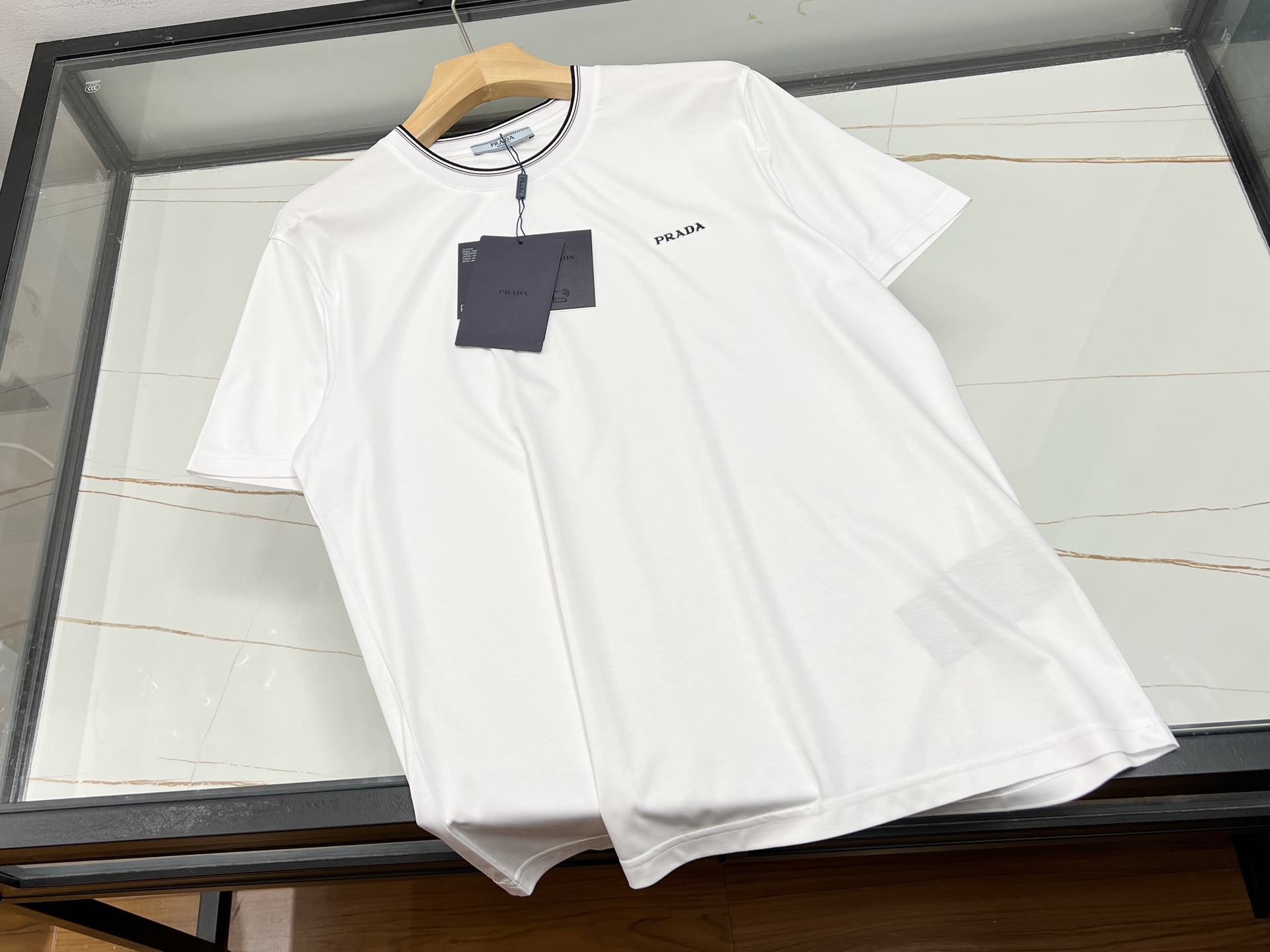 NO:821588,-26SS - Neck knitted threaded top woven letter short sleeves are a fashionable item in the spring and summer of 2026. This short sleeve is made of high-quality cotton fabric, combined with fine thread knitting technology, and letter elements are cleverly integrated into the neckline. The top knitting technology presents a three-dimensional effect, which not only adds a sense of design, but also improves the overall look.  Fashionable. Its shape is slim but not tight, making it suitable for a variety of body types. Whether paired with jeans or casual pants, you can easily show off your personality. In addition, this short-sleeved shirt is also very breathable and sweat-absorbent, making it suitable for spring and summer, allowing you to stay fashionable while enjoying a comfortable wearing experience.  Ready for sale in two colors M-XXXL, Prada-clothing, prada, jeans, T-shirt,19860909-26SS——领口针织螺纹顶织字母短袖,是2026年春夏季节的时尚潮流单品.这款短袖采用优质棉质面料,结合精细的螺纹针织工艺,领口处巧妙融入字母元素,通过顶织技术呈现立体效果,既增添了设计感,又提升了整体的时尚度.其版型修身而不紧绷,适合多种身材穿着,无论是搭配牛仔裤还是休闲裤,都能轻松展现个性魅力.此外,这款短袖的透气性和吸汗性也十分出色,适合春夏季节穿着,让你在保持时尚的同时,也能享受舒适自在的穿着体验. 现货发售二色M-XXXL,普拉达-服装,prada,jeans,T-shirt,,Women's clothing