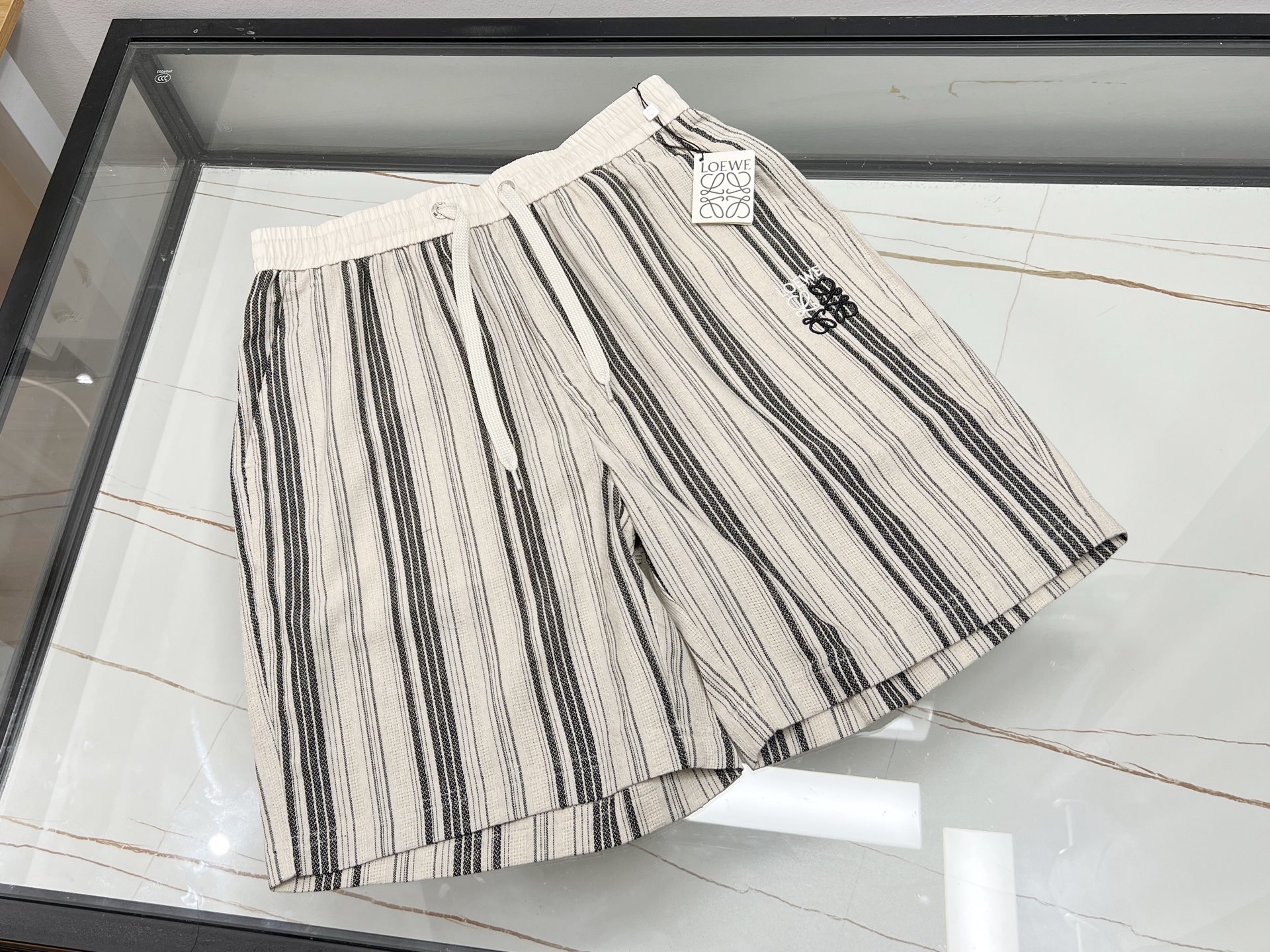 NO:860461,-26SS——LOW linen and cotton striped casual pants, an excellent choice for summer travel  These linen and cotton striped casual mid-pants perfectly combine the breathability of linen with the softness of cotton, bringing you the ultimate comfortable wearing experience. The classic striped design is simple yet fashionable, easily breaking the monotony. The mid-pants have a neat shape and can move freely without restraints. They can be adapted freely whether you are walking on the street, doing outdoor sports or relaxing at home. The details show quality, with neat stitching and fine workmanship. Paired with a simple T-shirt or a refreshing shirt, it instantly enhances the overall look and allows you to easily show your unique charm of casualness and handsomeness in summer.  Available now in two colors XS-S-M-L, Loewe-clothing, loewe, shirts, tees, t-shirt,19860909-26SS——LOW麻棉条纹休闲中裤,夏日出行的绝佳之选 这款麻棉条纹休闲中裤,将麻的透气与棉的柔软完美融合,带来极致舒适的穿着体验.经典条纹设计,简约又不失时尚感,轻松打破单调.中裤版型利落,活动自如无束缚,无论是漫步街头、户外运动还是居家休闲,都能自在适配.细节之处尽显品质,缝线工整,做工精细.搭配简约T恤或清爽衬衫,瞬间提升整体造型感,让你在夏日轻松展现随性又帅气的独特魅力. 现货发售二色XS-S-M-L,罗意威-服装,loewe,shirts,tees，t-shirt,,Women's clothing