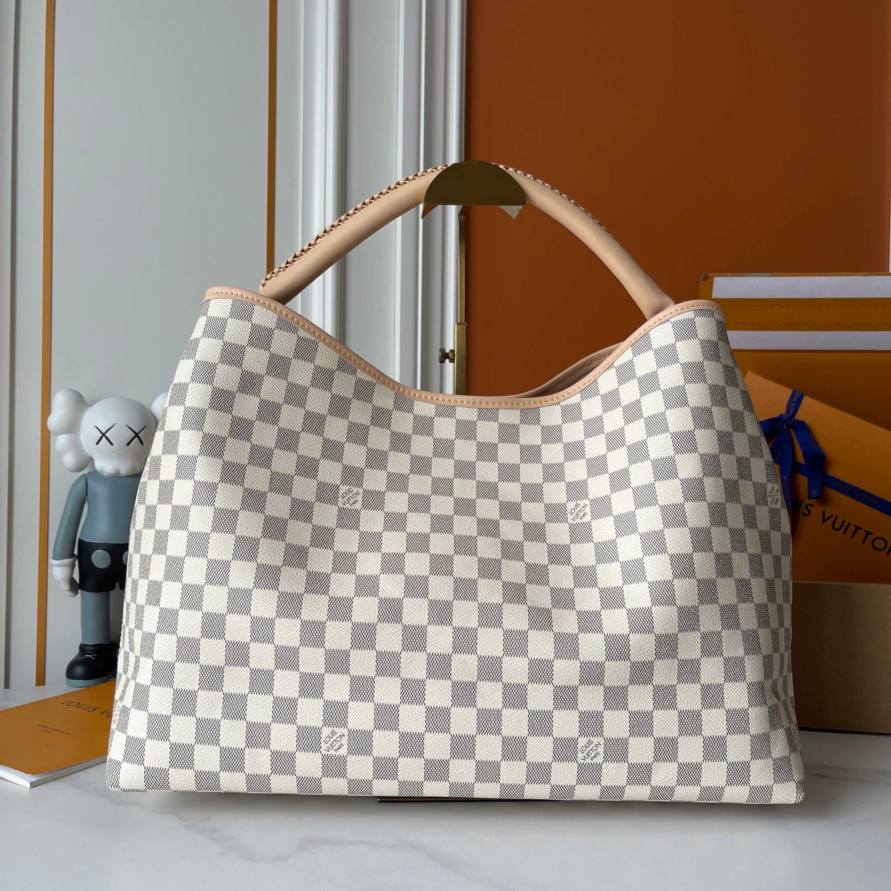 p290  M40249 M25877 Again手袋，这是对2010年首次推出的标志性Artsy设计的全新诠释，如今更加柔韧、更具标志性，且制作工艺更加精细。这款手袋植根于LV的DNA，通过经典的Monogram帆布基底、手工编织的提手以及可定制的姓名标签，向路易威登的精湛工艺致敬。其尺寸宽敞，足以容纳一台笔记本电脑，打开后可见多个口袋。金色的挂钩可用于挂上俏皮的饰品！！尺寸:50x30x15.5CM