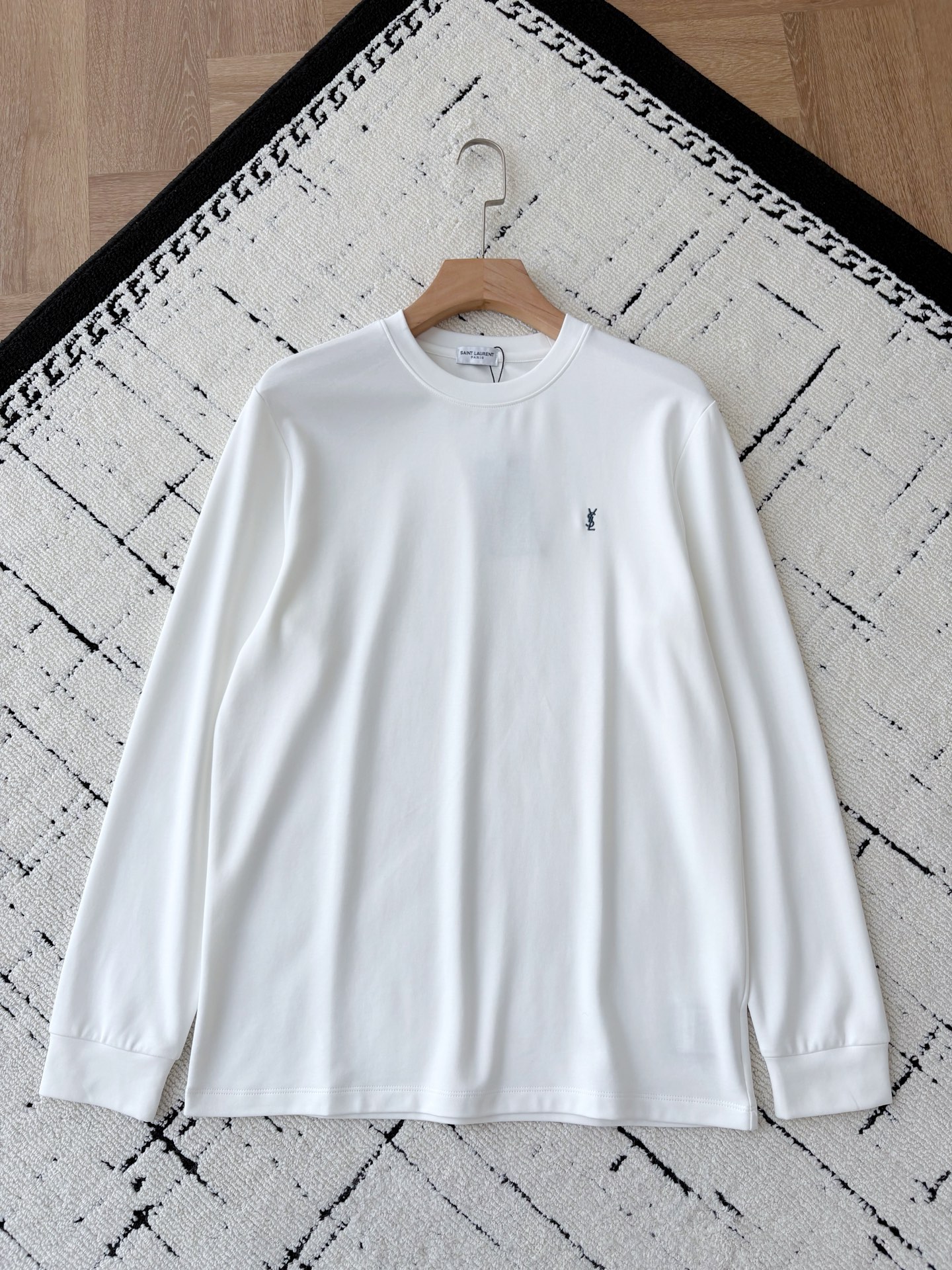 NO:571248,The combination of YSL luxury-grade textured long-sleeved T-shirt Tencel Modal and wool. The silky luxury of Tencel Modal meets the warmth, softness and skin-friendliness of wool. A long-sleeved T-shirt that redefines 'luxury everyday' was born.  The outer layer is made of Tencel modal blended fabric, which feels as smooth as satin at the touch of your fingertips. It has a low-key and high-end luxury luster when you walk, making the simple version more exquisite. The inner woolen fleece wraps the body like a gentle warmth, and is very close to the skin. It is warm and has no sense of restraint when wearing it in autumn and winter.   The iconic brand YSL embroidery is embellished on the chest, and the details are full of style. Whether worn alone to create a light luxury style, or layered to create a layered look, it can be easily held. From fabrics to craftsmanship, everything tells the definition of 'extreme quality', allowing you to touch the luxury temperature at any time in your daily wear. Same style for men and women, black, blue and white; XS-L size; 1-3CM error when measuring flat.  XS code: shoulder width 44 bust 102 dress length 70 sleeves 61 S code: shoulder width 45 bust 106 dress length 72 sleeves 62 M code: shoulder width 46 girth 110 dress length 74 sleeves 63 L code: shoulder width 47 bust 114 dress length 76 sleeves 64 Girls choose XS code; boys under 135 pounds choose XS code; 135-150 pounds choose S code;   For 150-jin, choose M size; for 185-jin, choose L size.,,saint laurent,tees,t-shirt,silk fabric,alexander wang19860909YSL奢品级质感长袖T恤天丝莫代尔与羊毛绒的结合 当天丝莫代尔的丝滑奢光邂逅羊毛绒的暖柔亲肤,一件重新定义“奢华日常”的长袖T恤就此诞生. 外层采用天丝莫代尔混纺面料,指尖轻触便是绸缎般的顺滑质感,行走间泛着低调又高级的奢品光泽,将简约版型衬得愈发精致；内里羊毛绒加持,像把温柔暖意裹在身上,亲肤度拉满,秋冬穿着既保暖又毫无束缚感. 标志性的品牌YSL刺绣点缀胸前,细节处尽显格调.无论是单穿塑造轻奢风,还是叠穿打造层次感,它都能轻松hold住.从面料到工艺,每一处都在诉说着“极致品质”的定义,让你在日常穿搭中,随时能触摸到奢华的温度. 男女同款,黑色 蓝色 白色 ；XS-L码； 平铺测量1-3CM误差 XS码:肩宽44胸围102衣长70袖子61 S码:肩宽45胸围106衣长72袖子62 M码:肩宽46围110衣长74袖子63 L码:肩宽47胸围114衣长76袖子64 女生选择XS码； 男生 135斤以下选择XS码；135-150斤选择S码； 150-斤选择M码；-185斤选择L码.,,saint laurent,tees，t-shirt,silk fabric,alexander wang,Men's clothing