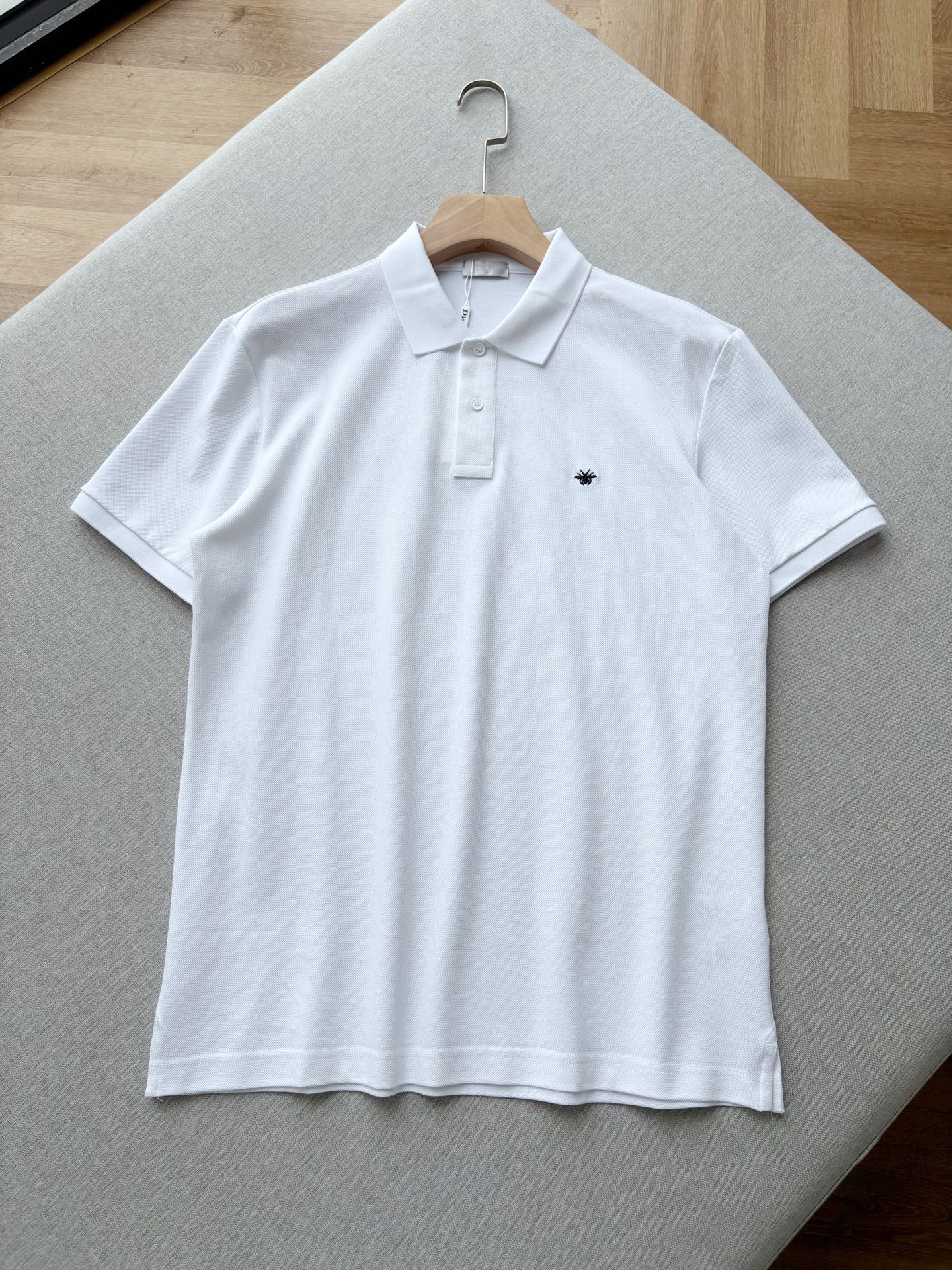 NO:845037,Di Classic Bee Embroidered Pique Cotton Polo Shirt This Polo is a timeless wardrobe classic. It has a classic lapel and a two-button placket. It is neatly tailored to fit all body shapes. The small bee embroidery on the chest is an iconic status symbol. It is available in black, white and navy blue. It is low-key and has a sense of luxury, and can be worn for commuting and leisure.  Combed pique cotton fabric, the fine and breathable mesh texture has a cool feeling, is skin-friendly and not sweaty, has a perfect balance of drape and stiffness, and will not be easily deformed after long-term wear. It is also refreshing and comfortable to wear in summer. The same color binding stitching, slightly rolled cuffs, and side slit design on the hem hide exquisite workmanship in every place. There is no redundant logo but the quality is everywhere. It is a classic that can be worn for many years. Men's model, black, white, blue, XS-XL size.  Flat measurement error 1-3CM XS code: shoulder width 46 bust 106 dress length 71.5 sleeves 22 S size: shoulder width 47 bust 110 dress length 73 sleeves 22.5 M size: shoulder width 48 chest 114 dress length 74.5 sleeves 23 L size: shoulder width 50 chest 118 dress length 76 sleeves 23.5 XL code: shoulder width 52 chest 122 dress length 77.5 sleeves 24  Recommended size chart: Choose XS size if you are under 135 catties, choose S size if you are 135-150 catties, choose M size if you are 150-165 catties, choose L size if you are 165-180 catties, and choose XL size if you are 180-200 catties.19860909Di经典蜜蜂刺绣珠地棉Polo衫 这件Polo是永不过时的衣橱 经典,经典翻领+两粒扣门襟,利落剪裁适配各种身形；胸口小巧蜜蜂刺绣是标志性身份符号,黑白藏青三色可选,低调中透着高级感,通勤休闲都能hold住. 精梳珠地棉面料,细密透气的网眼肌理自带凉感,亲肤不闷汗,垂坠感与挺括度平衡得恰到好处,久穿不易变形,夏天穿也清爽舒适. 同色包边缝线、袖口微卷工艺、下摆侧开叉设计,每一处都藏着精致做工,无多余logo却处处彰显品质,是能穿很多年的经典. 男款,黑色 白色 蓝色,XS-XL码. 平铺测量1-3CM误差 XS码:肩宽46胸围106衣长71.5袖子22 S码:肩宽47胸围110衣长73袖子22.5 M码:肩宽48胸围114衣长74.5袖子23 L码:肩宽50胸围118衣长76袖子23.5 XL码:肩宽52胸围122衣长77.5袖子24 尺码表推荐: 135斤以下选择XS码,135-150斤选择S码, 150-165斤选择M码,165-180斤选择L码, 180-200斤选择XL码.,,,Men's clothing