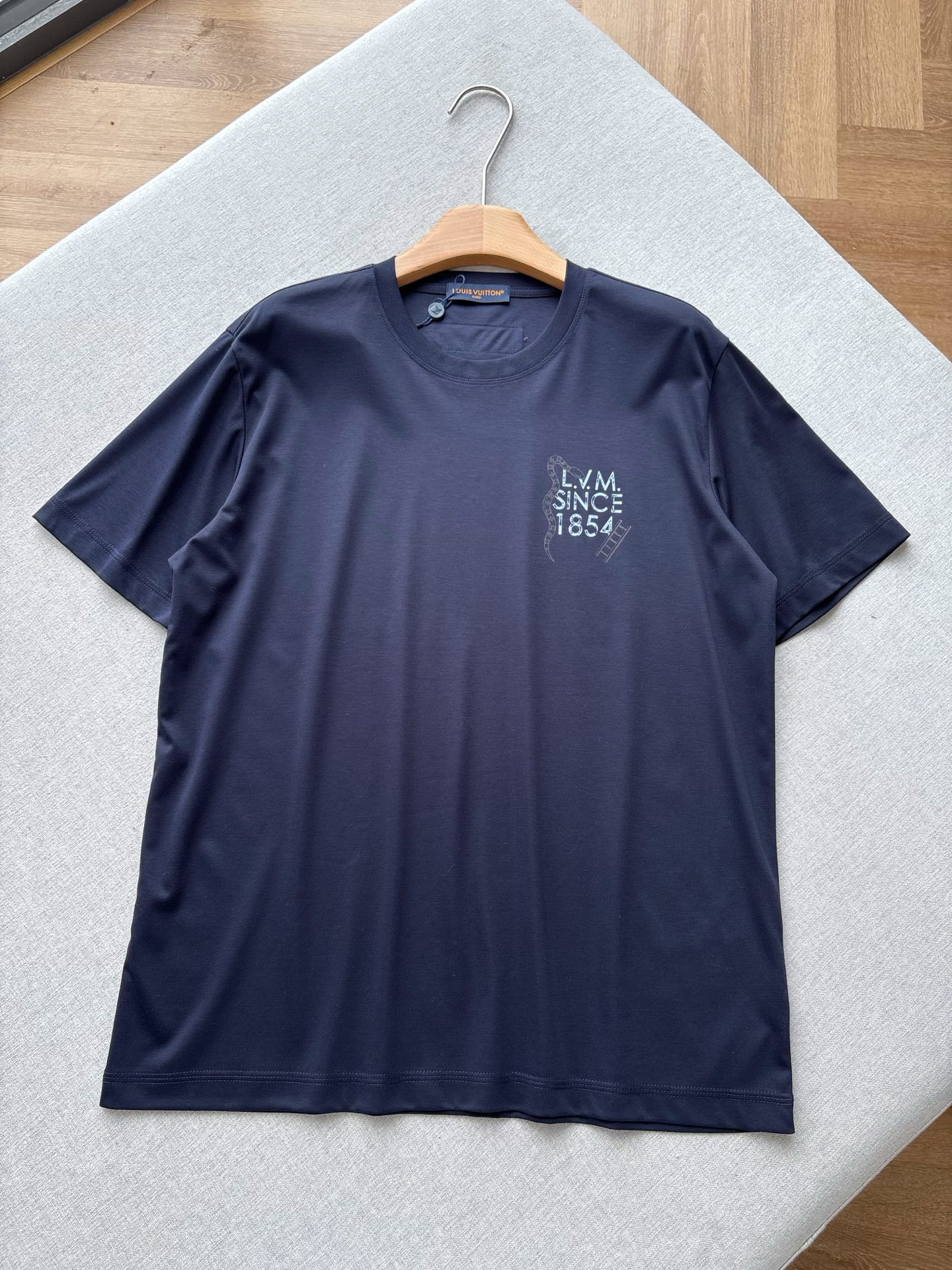 NO:845043,V Navy Liquid Nitrogen T｜Snake Ladder Letter Printed Short Sleeves. High-count and high-density long-staple cotton fabrics are selected. After liquid nitrogen cold treatment, the hand feels as smooth and soft as liquid. It has ice-like cooling properties. The upper body is cool but not ice, and it is moisture-wicking and full. Dark navy blue color, low-key and high-end, not picky on skin tone. The chest adopts the old-style 'L.V.M SINCE'  The 4' letter print is paired with the brand's iconic snake and ladder elements, and the brand DNA is hidden in the details. The printing uses high-definition offset printing technology, which has strong adhesion, does not crack or fall off, and can keep the texture online even when washed. The old light tone is looming on the dark clothes, not exaggerated but self-recognizable, which perfectly interprets V's low-key luxury aesthetics. The iconic orange leather label on the back, as the brand's hidden logo, is low-key yet high-end, and the wiring is neat and solid.  The hem adopts double-strand thread + chain thread technology, which is smooth and firm, washable and durable, and has unlimited movement. Same style for men and women, navy blue, XS-XL size; 1-3CM error in flat measurement. XS size: shoulder width 46, chest size 106, dress length 67, sleeve length 22.5. S size: shoulder width 47, chest size 110, dress length 69, sleeve length 23.  L code: shoulder width 49, bust 118, shirt length 73, sleeve length 2419860909V藏青色液氮T｜灵蛇爬梯字母印花短袖 甄选高支高密长绒棉面料,经过液氮冷处理工艺,手感如液态般丝滑软糯,自带冰感降温属性,上身凉而不冰,吸湿排汗性拉满. 深海军蓝藏青色调,低调高级不挑肤色.胸口采用做旧风格的“L.V.M SINCE 4”字母印花,搭配品牌标志性的灵蛇与爬梯元素,细节里暗藏品牌DNA. 印花采用高定胶印工艺,附着力强、不开裂、不脱落,水洗也能保持质感在线,做旧的浅色调在深色衣身上若隐若现,不浮夸却自带辨识度,完美诠释了V的低调奢华美学.后背标志性的橙色皮标,作为品牌隐藏标识,低调又高级,走线工整扎实. 下摆采用双股线+锁链线工艺,走线平整牢固,耐洗耐穿,活动不受限. 男女同款,藏青色,XS-XL码； 平铺测量1-3CM误差 XS码:肩宽46胸围106衣长67袖长22.5 S码:肩宽47胸围110衣长69袖长23 M码:肩宽48胸围114衣长71袖长23.5 L码:肩宽49胸围118衣长73袖长24 XL码:肩宽50胸围122衣长75袖长24.5 女生选择XS码； 男生 135斤以下选择XS码；135-150斤选择S码； 150-165斤选择M码；165-180斤选择L码； 180-斤选择XL码.,,T-shirt,,Men's clothing