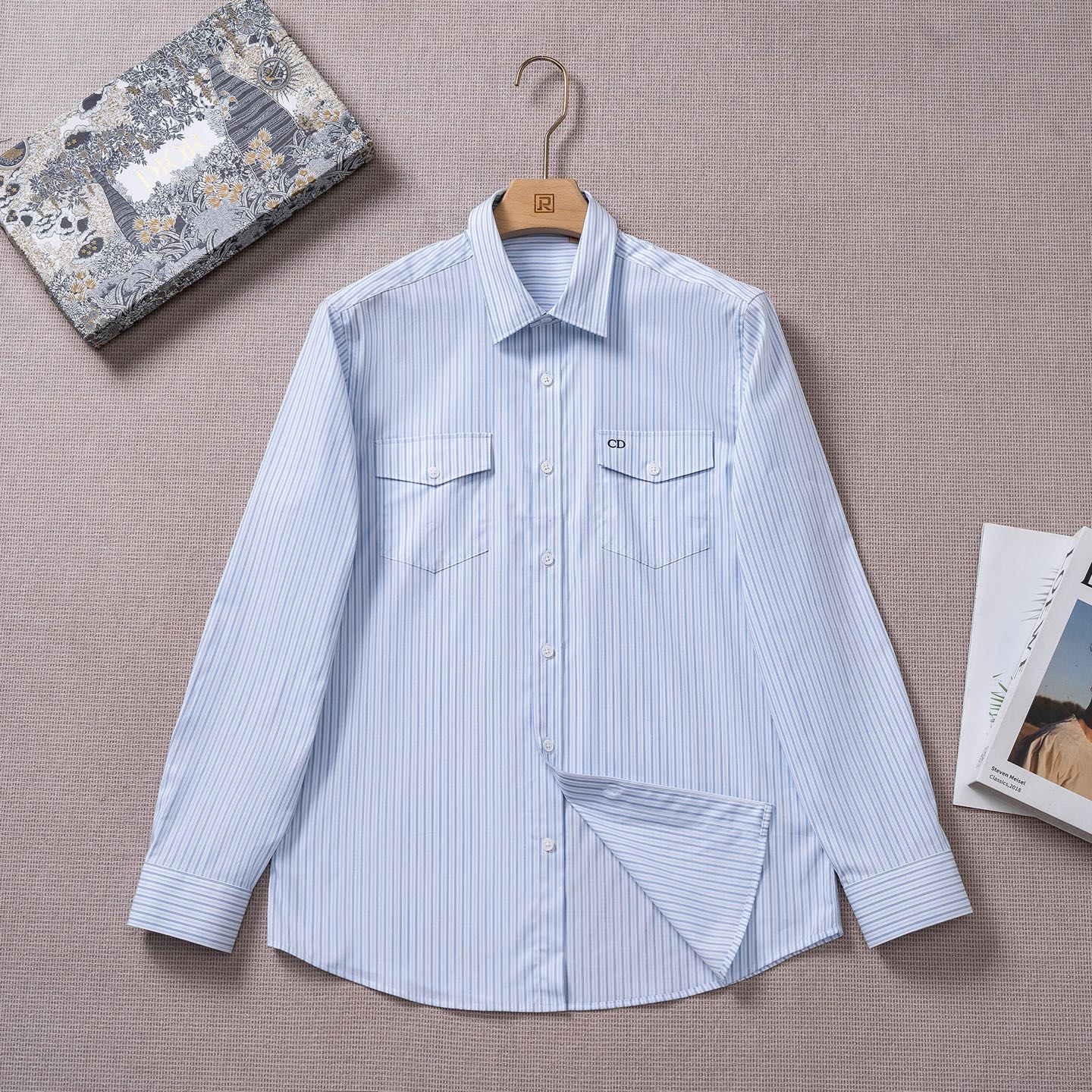 NO:844573,[New product launch] D’s 26 spring and summer fashion style long-sleeved shirt!  The high-end fashion aesthetic design combined with the three-dimensional cutting version makes the wear more comfortable and ornamental. The top-grade Swiss ALUMO company's 120-count blue striped cotton poplin has excellent texture and comfort, and the texture and texture reveal a sense of high-end. The buttons are natural deep-sea shell buttons, each one has a unique texture and an excellent luster!  Exquisite tailoring is the essence of the exquisite craftsmanship of the D family workshop and the core of the D family heritage. This shirt made a wonderful debut at Jonathan Anderson's D family show, reinterpreting the elegance of the classic silhouette. The D family Icons series reflects the exquisite craftsmanship and fine tradition of the D family with an elegant and casual style. This shirt is carefully made of 120-count blue striped cotton poplin fabric and decorated with CD  Embroidery, decorated with flap patch pockets on the chest, unique. Exquisite details, can create a variety of casual looks. Size 38-42, size 39, shoulder width 46, bust 108, sleeve length 62.5, clothing length 76,, dior, shirts,19860909【新品上市】D家26春夏时装款长袖衬衫！ 高端的时尚美学设计结合立体裁剪的版型,使穿着更具舒适性和观赏性. 甄选甄选的顶级瑞士ALUMO阿鲁姆公司120支蓝色条纹棉府绸,质感与舒适度绝佳,肌理纹路透着高级感. 纽扣为天然深海贝壳扣,每粒都有着独一无二的纹路,光泽感极好！ 考究的剪裁是D家工坊精湛工艺的精髓所在,也是D家传承的核心.这款衬衫于乔纳森·安德森 (Jonathan Anderson) 的D家首秀精彩亮相,重新诠释经典廓形的优雅.D家Icons 系列以优雅随意的风格彰显D家的精湛工艺和优良传统. 这款衬衫采用120支蓝色条纹棉府绸面料精心制作,饰以 CD 刺绣,胸前饰以翻盖贴袋,别具一格.细节精巧,可打造各式休闲造型. 尺码38-42 39码 肩宽46 胸围108 袖长62.5 衣长76,,dior,shirts,,Men's clothing
