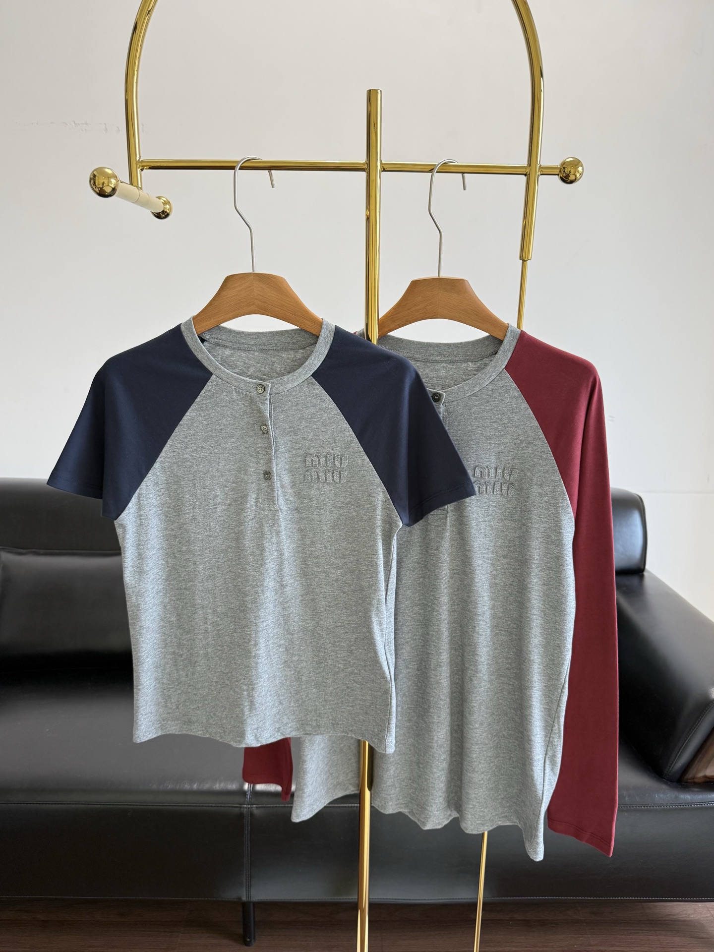 NO:739120,Short-sleeved long-sleeved miumiu same style 26Ss early spring new long-sleeved collar button T-shirt pure cotton fabric!  Inspired by American retro baseball shirts, the classic raglan sleeve design is used to reshape the college style. The calm gray tones and warm red tones collide to create a vivid visual tension. The three-button detail on the neckline adds a sense of style. It can be opened to create a V-neck effect, or it can be buttoned to keep it neat. Three-dimensional appliqués on the chest.  The logo is low-key and recognizable. The soft cotton blended fabric is both comfortable and stiff. The fit is tailored to fit the body shape without being tight. Paired with a white work skirt, it is a sweet and cool girl style. It can be worn with jeans for a casual and relaxed feeling. It is a versatile item that can be worn layered or alone in early spring.  Size sml short sleeve long sleeve,,miumiu,skirts,jeans,T-shirt,tees,t-shirt,19860909短袖长袖 miumiu同款 26Ss早春新款 长袖领扣T恤 纯棉面料！以美式复古棒球衫为灵感,用经典插肩袖设计重塑学院风.沉稳灰调与热烈红调碰撞出鲜活的视觉张力,领口三颗纽扣细节增添了造型感,可敞开打造V领效果,也可扣合保持利落.胸前立体贴布绣Logo低调彰显辨识度,柔软的棉混纺面料兼具舒适度与挺括感,合身剪裁贴合身形却不紧绷.搭配白色工装裙是甜酷少女风,配牛仔裤又能穿出随性松弛感,是早春叠穿与单穿都出彩的百搭单品 码数sml 短袖 长袖,,miumiu,skirts,jeans,T-shirt,tees，t-shirt,,Women's clothing