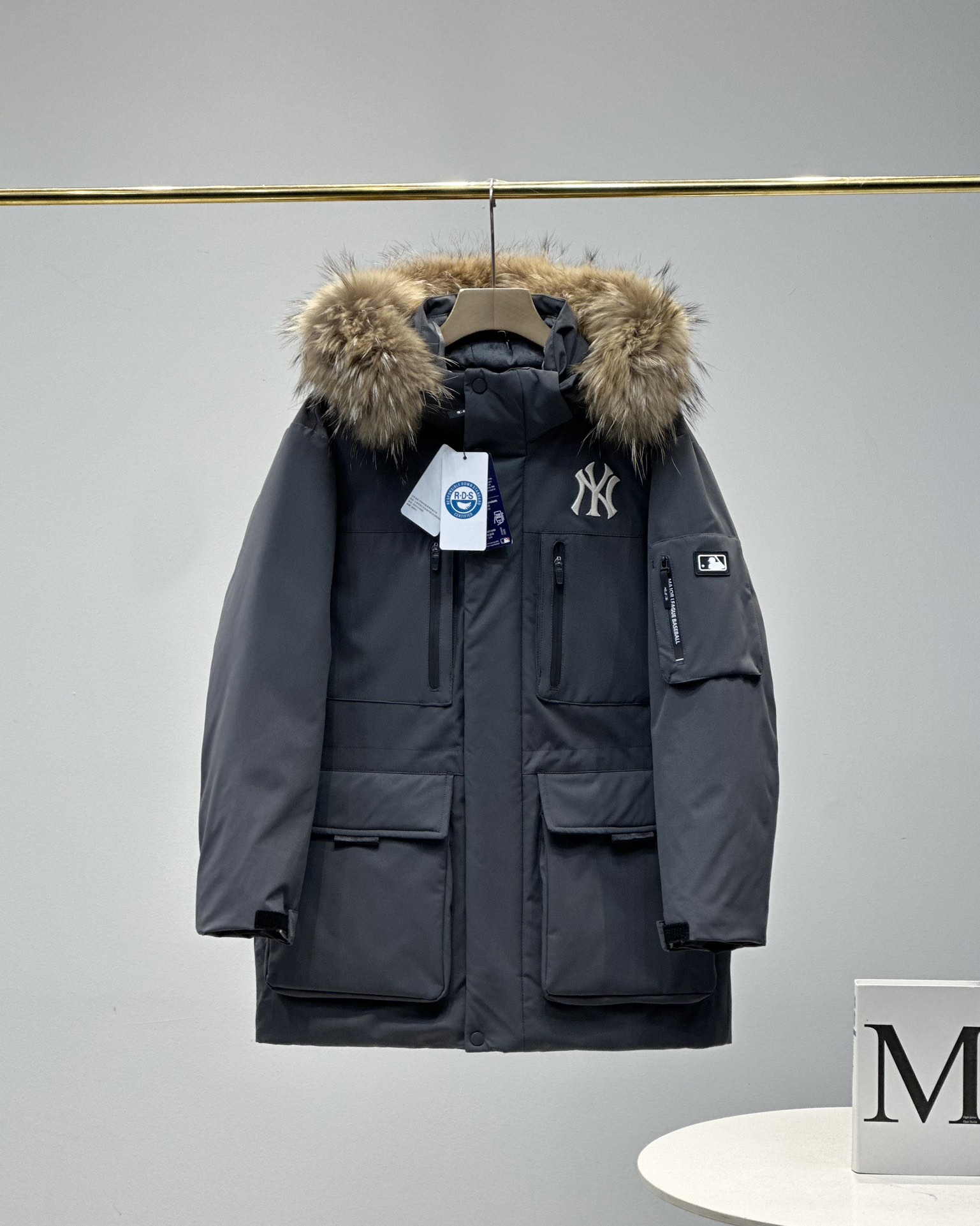 顶级💰450 代购级💰550 正品级💰680  
五色齐发  奢华真毛领 区别市场任何毛领 ）
MLB/男女24冬季新款张凌赫同款鹅绒毛领加厚羽绒服户外中长款外套💗（原单货）
区别普通版本！🉑对比毛领➕细节➕三标水洗👍
明星同款，机能风潮，时尚有型。
张凌赫今年代言的海报上身款！出席店庆活动时也是身着这款！可谓今年品牌的主力款式！
工装风多口袋设计，面料不是薄薄一层，是手感厚实的定制三防面料，防风防泼水。袖臂和前胸拉链都是采用防水拉链。户外穿着更保暖！
柔软真皮草毛领，大大的一整根貉子毛领，不仅挡风保暖，更加的显奢华质感，一眼贵价羽绒服！
胸口重工贴布&ldquo;刺绣&rdquo;MLB标志性的NY logo，袖臂插袋饰有经典的硅胶标，品牌辨识度极强。
中长款，长度盖住臀部，针织双层袖口，抵御寒风，东北极寒都是妥妥的能扛住！！
填充国标600蓬90白鹅绒！打开后挂起来拍打一下，静待毛领和衣服舒展蓬起来！
帽子和下摆自带可调节抽绳和锁扣，包裹暖意，随心自如！
大厂工艺精细，走线工整！ 细节处理完美😘
四个色，黑色 白色是永远的经典，怎么穿都好看。浅藏青颜色质感非常高级。浅驼色特别色 显白 穿着好看🈶气质👍

颜色。黑色    奶白色    浅青色     浅驼色   灰色
尺码XＳ&mdash;XXL
尺码   衣长    肩宽   胸围     袖长    推荐体重
XS       76       50     120       60    80-100
S        78       51     122       61      100-120
Ｍ       80       52    126       62      120-140
L        82       53     130      63.5    140-160
XL      84       54     134      64.5    160-180
XXL    86       55     138      65.5    180-200

​