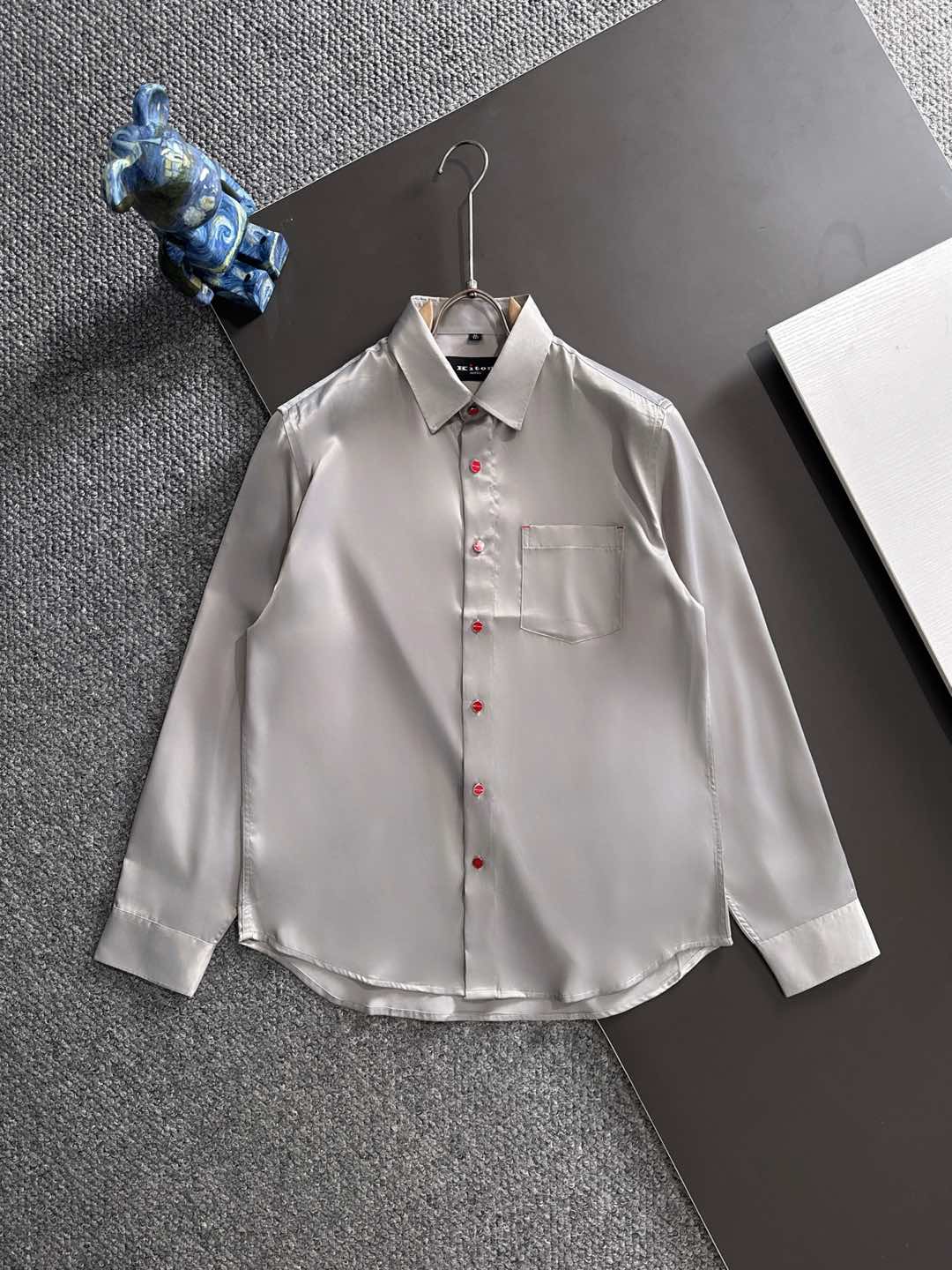 NO:528797,Kiton's new 25-year-old style. Fall in love with the little red button. Unlocking the free philosophy of gentlemen's new realm shirts. Among the thousands of choices of dress, some items are like low-key gentlemen, which seem ordinary, but actually hide the world. This casual long-sleeved shirt with customized fabrics is one of the best, especially the unique little red button, which has become the finishing touch and makes countless men fall in love with. The soft feel brings you a comfortable wearing experience. The shirt adopts a classic pointed collar design, which originated from the British royal family and is a symbol of elegance and elegance. The corners of the neck are sharp and slightly turned outward, which perfectly highlights the men's neckline. Whether it is paired with a tie to create a formal business style or unbutton the neckline and act casually, it shows the gentleman's demeanor. Wearing it instantly enhances the aura, whether it is business negotiations, social gatherings or daily travel, you can be confident.  And the small red button is definitely the soul of this shirt. In a plain or elegant tone, the bright red quietly appears, breaking the conventional dullness. It is like a mysterious symbol, low-key but highly recognizable, inadvertently revealing the wearer's unique taste and personality. When the breeze blows, the shirt swings in the wind, the red button appears faintly, becoming the visual focus of the crowd, adding a playfulness and agility to the overall look. This casual long-sleeved shirt for men, perfectly blending the unique charm of classic elegance and small red buttons, is a fashion item that men who pursue quality and personality cannot miss. Wear it, embrace freedom and comfort, and show the unique charm of gentlemanly.19860909Kiton25年新款.爱上小红扣.解锁绅装新境界衬衫的自在哲学 在着装的万千选择中,有些单品宛如低调的绅士,看似平凡,实则暗藏乾坤.这款甄选定制面料的休闲长袖衬衫,便是其中的佼佼者,尤其是那独特的小红扣,成为了点睛之笔,令无数男士为之倾心. 手感柔软为你带来惬意的穿着体验. 衬衫采用经典尖领设计,这种领型起源于英国王室,是优雅与精致的象征.领角尖锐且微微外翻,能够完美地衬托出男士的颈部线条,无论是搭配领带打造正式商务风,还是解开领口随性而为,都尽显绅士风度.穿上它,瞬间提升气场,无论是商务洽谈、社交聚会还是日常出行,都能自信满满. 而那小巧的小红扣,绝对是这款衬衫的灵魂所在.在一片素色或淡雅的色调中,那一抹鲜艳的红悄然出现,打破了常规的沉闷.它像是一个神秘的符号,低调却又极具辨识度,不经意间流露出穿着者独特的品味与个性.当微风轻拂,衬衫随风摆动,小红扣若隐若现,成为了人群中的视觉焦点,为整体造型增添了一份俏皮与灵动. 这款男士休闲长袖衬衫,经典优雅以及小红扣的独特魅力完美融合,是追求品质与个性的男士们不可错过的时尚单品.穿上它,拥抱自由与舒适,展现独特的绅士魅力. 码数M-3XL,,shirts,ties,alexander wang,Men's clothing