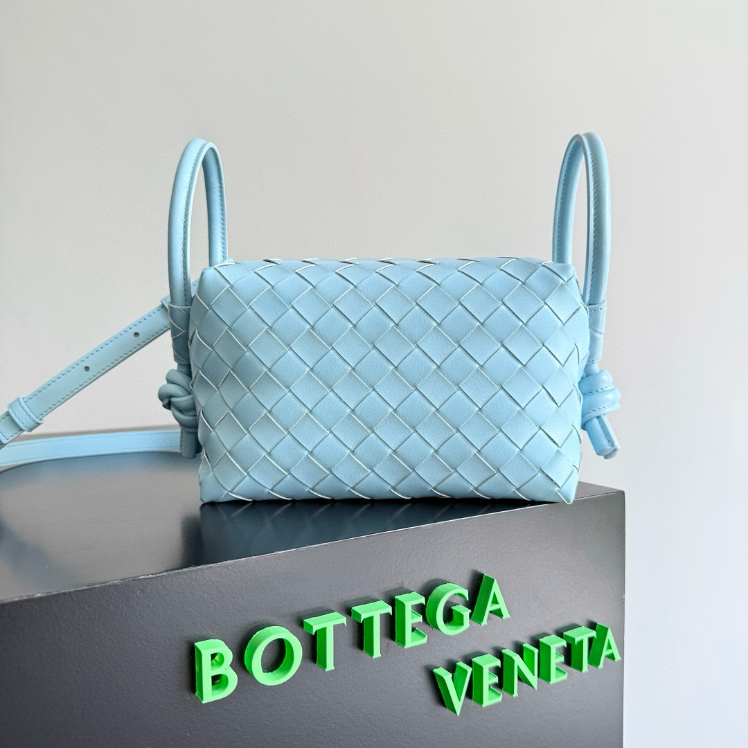The BOTTEGA VENETA 2024 new Loop is here! Many BV fans have owned the Loop bag—simple design, classic weaving, compact and lightweight. This innovation continues the "camera bag" style but now allows both hand-carry and crossbody wear, unlike the traditional Loop which was only crossbody. The oversized ring clasp lets you fold the bag or use it as a handle. Perfect for summer, this lightweight bag boosts your travel comfort.  
Style number: 796615  
Size: 19 x 12 x 9 cm image 1