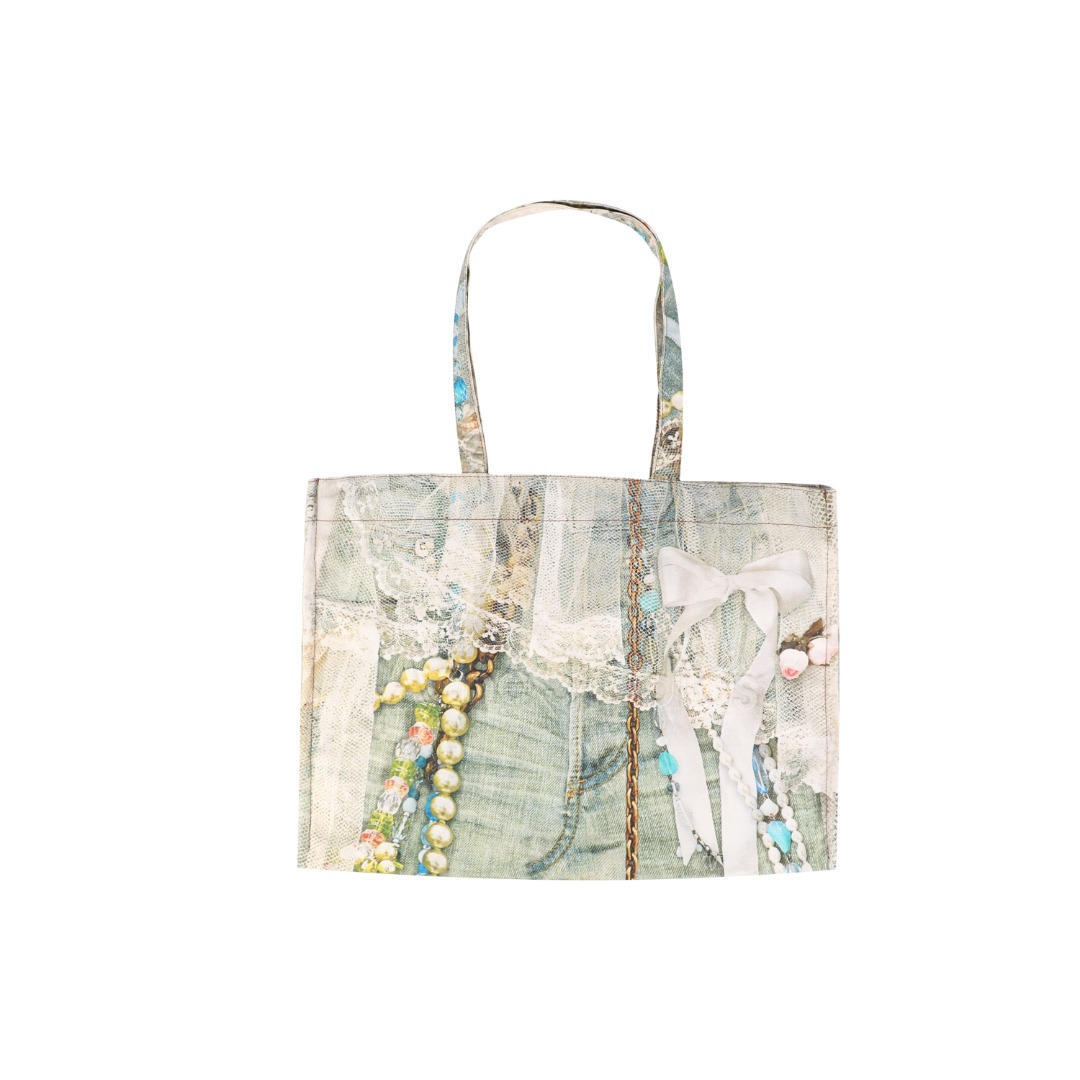 #Acne Studios 25Fw 蕾丝珍珠印花牛仔托特包 采用高密双股纱线织造，克重达420g/㎡，表面呈现粗粝斜纹肌理，同时通过预缩酵素洗处理确保尺寸稳定性，赋予包体挺括骨架感与抗变形性能，选用进口数码直喷机，实现1200dpi高清印花，通过6色纳米墨水层叠渗透技术，将“蕾丝裤”图案以微米级精度附着于帆布纱线间隙，形成立体浮雕触感。匹布印后经UV固化与硅油柔化处理，确保图案耐水洗、抗摩擦，使用兄弟BAS双针平缝机，配置16号钛涂层牛仔针与Tex 70高弹涤纶线，在包体侧缝及底部间距同步车缝双线，形成平行受力通道，分散承重压力。三次元回针加固，在拎手锚点、包角应力区采用电脑程式化回针，配合背面热熔胶衬垫，形成机械-化学双重复合固定，此设计通过材料科学与精密缝制技术的交叉应用，实现柔美意象与重型帆布机能结构的对立统一，体现ACNE对当代工艺美术化的极致追求 尺码：47×17×35-选品中心