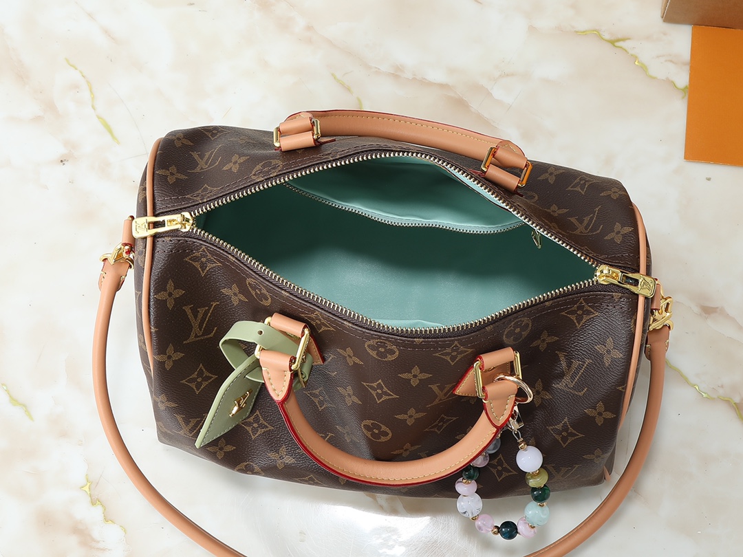 💰130💰升级原版 M15107 M12803 M11945 M12243 M87212 M40391 Speedy Soft 30 Boho 手袋取材经典 Monogram 涂层帆布，再以皮革内衬和拉链内袋注入色彩反差。鸵鸟皮革饰边和珠链汇聚视觉焦点，钥匙包和地址牌共筑巧思细节，Toron 手柄实现多种背携方式。尺寸:30.0 x 21.0 x 17.0 厘米 (长 x 高 x 宽)