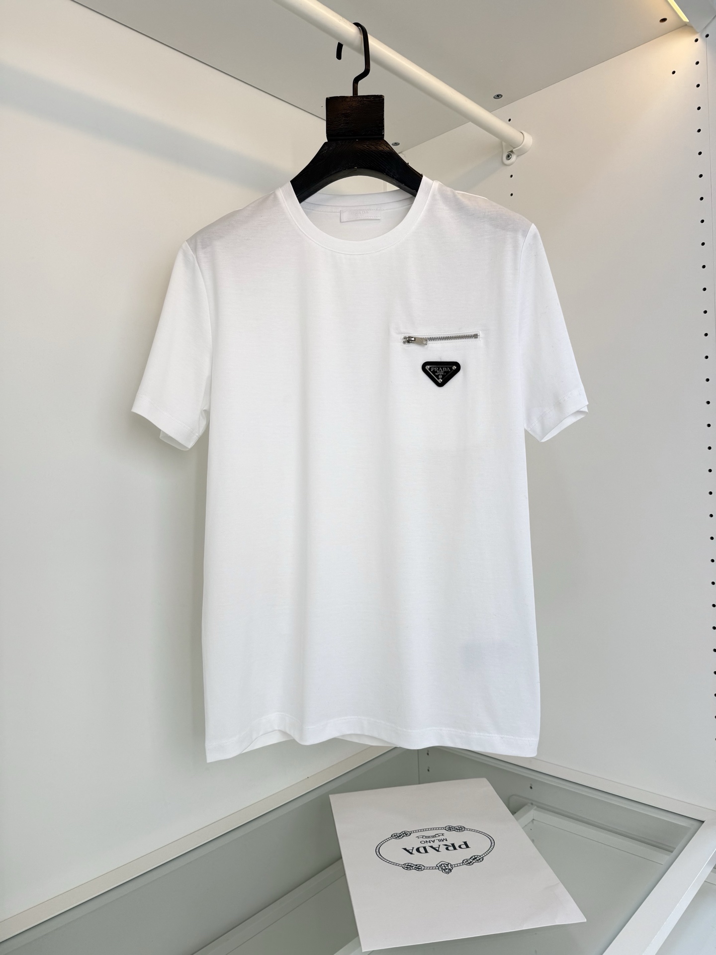 NO:701076,PR*DA 2026 Spring and Summer Annual Classic Nylon splicing design mercerized cotton round neck T-shirt, nylon splicing design. The zipper pocket on the chest is embellished with a triangle logo. You can feel the theme on the upper body, which brings a sense of youth and fashion. Fitted tailoring, the collar slightly fits the neck, making the overall upper body more youthful and fashionable. Before cutting, the fabric is strictly in accordance with the standards of 5 washes before dyeing, and the shrinkage rate is controlled within 2.  The fabric is made of custom-woven high-weight pure cotton, treated with mercerization process. The surface has a warm luster, the upper body is comfortable and smooth, and looks high-end. It is skin-friendly, breathable, and has a good stiff feeling. Color Black White Size M-319860909PR*DA普*达 2026春夏 年年经典 尼龙拼接设计丝光棉圆领T恤衫,尼龙拼接的设计 胸口拉链口袋结合三角标点缀 上身就能体会主题带来年轻与时尚感 合体的的剪裁,领口微微贴合颈部,让整体上身更显年轻时尚 ,面料在裁剪前,严格按照染色前5次 洗水的标准, 将缩水率控制在2内, 面料采用客供定织高克重纯棉质地,丝光工艺处理 表面有着温润的光泽感,上身舒适顺滑,显高档 亲肤 透气,又有很好挺括感 颜色 黑色 白色 码数M-3XL 试穿172-148 穿L码修身感,普拉达-服装,prada,tees，t-shirt,,Women's clothing