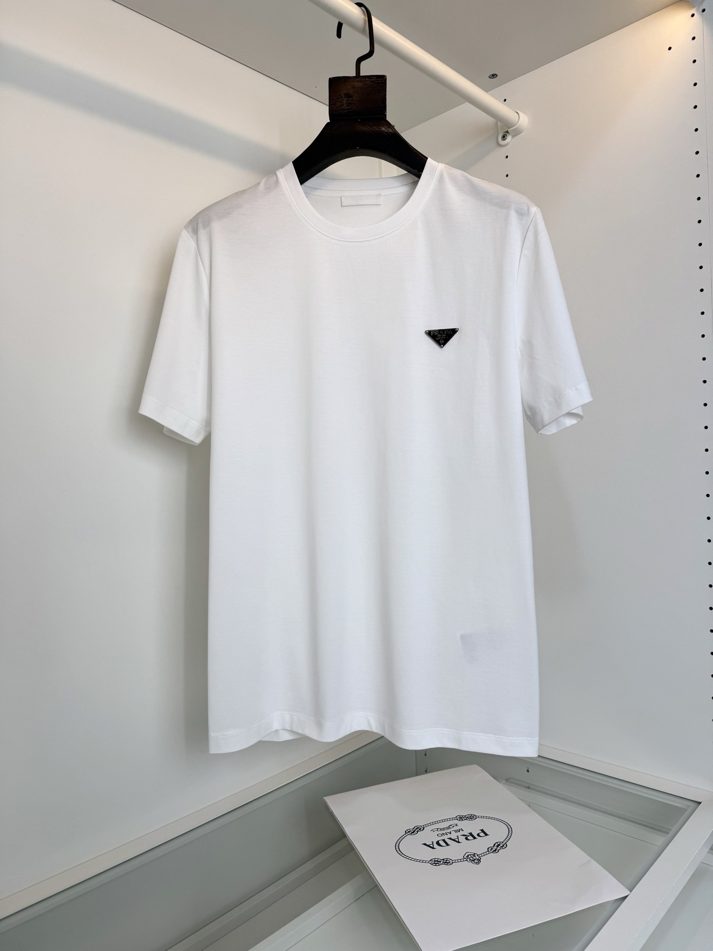 NO:743286,The highest version on the market, the girl inspects the goods, trims the three marks on the threads, and delivers the goods. You can post pictures and take videos. If you want quality and service, add me on WeChat. We will not accept urgent orders. PR*DA 2026 Spring and Summer Annual classic triangle logo embellished round neck short-sleeved T-shirt, annual classic triangle logo design. Metal logo embellishment design can be matched well whether worn inside or outside. The upper body feels young and fashionable.  Fitted tailoring, the collar slightly fits the neck, making the overall upper body look more youthful and fashionable. Before cutting, the fabric is strictly washed according to the standard of 5 times before dyeing, and the shrinkage rate is controlled within 2. The fabric is made of custom-made high-weight pure cotton and treated with mercerization process. The surface has a warm luster, the upper body is comfortable and smooth, and looks high-end. It is skin-friendly, breathable, and has a good sense of stiffness. Color Black White Size M-3XL  Try on 172-148, wear size L for slim fit, Prada-clothing, prada, T-shirt, tees, t-shirt,19860909市面最高版本小妹验货、修剪线头上三标、发货可发图及拍视频,要品质要服务的加我微信,不接急单. PR*DA普*达 2026春夏 年年经典三角标点缀圆领短袖T恤衫,年年经典三角标的设计 金属标的点缀设计 不管内搭还是外穿 都能很好搭配 上身感年轻与时尚 合体的的剪裁,领口微微贴合颈部,让整体上身更显年轻时尚 ,面料在裁剪前,严格按照染色前5次 洗水的标准, 将缩水率控制在2内, 面料采用客供定织高克重纯棉质地,丝光工艺处理 表面有着温润的光泽感,上身舒适顺滑,显高档 亲肤 透气,又有很好挺括感 颜色 黑色 白色 码数M-3XL 试穿172-148 穿L码修身感,普拉达-服装,prada,T-shirt,tees，t-shirt,,Women's clothing