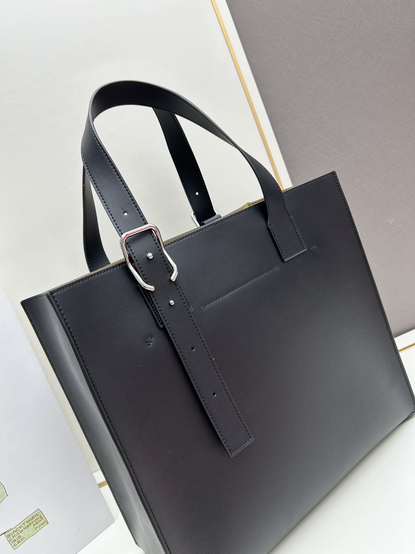 780 Loewe Buckle Tote 不带拉链 荔枝纹深灰手袋 男仕灰色托特包，型號3050 宽大的容量和纤细的轮廓。扁平和不对称的双顶部手柄，饰有标志性的弧形开口搭扣，可通过链扣调节，适合不同的携带方式。主要特点：偏宽扁平矩形包身，内部拉链口袋，两个缝合插袋隔层，真皮里里，Anagram压印点缀 尺寸36-33-17cm