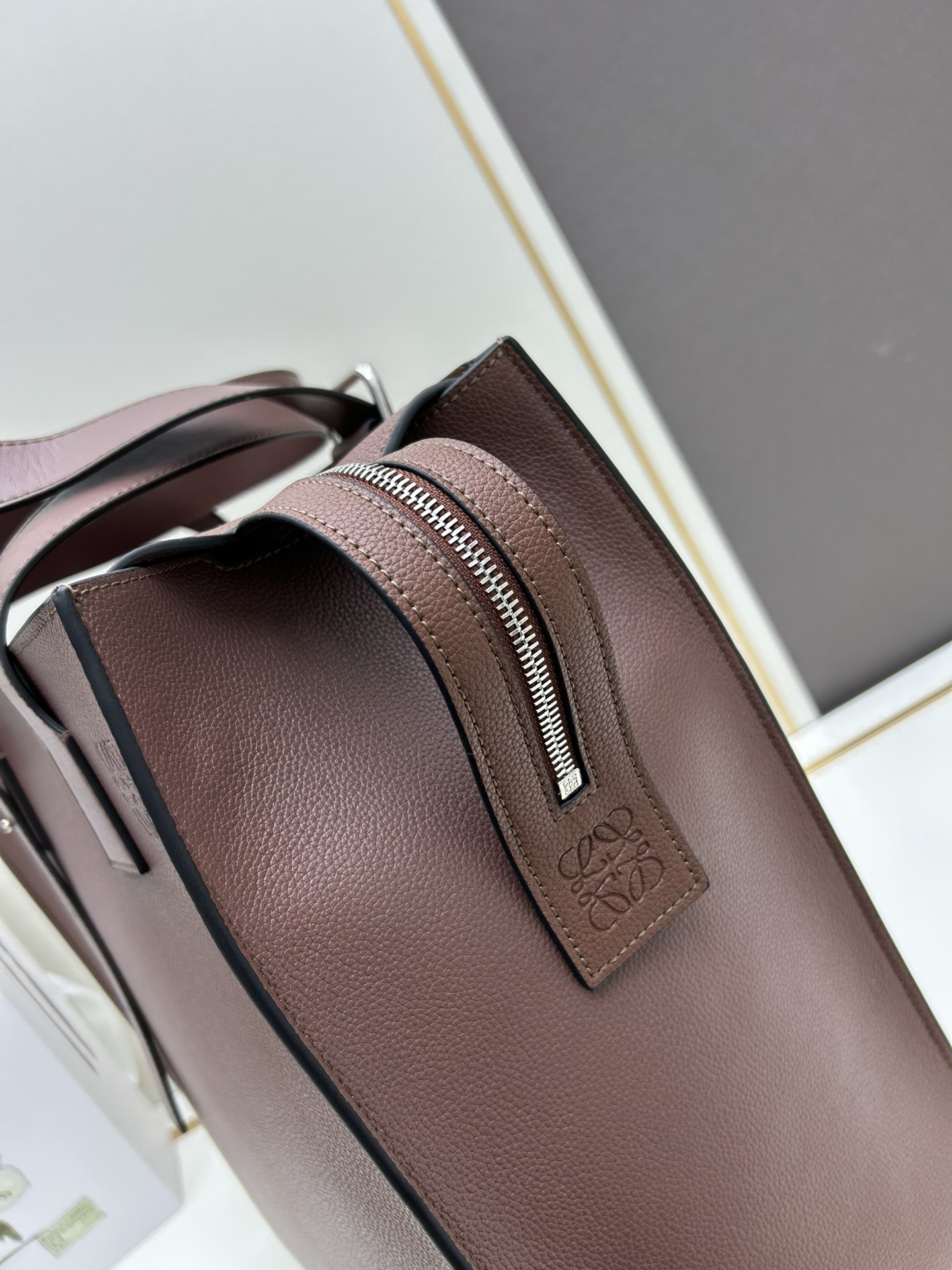 800 Loewe Buckle Tote手袋 新版本带拉链 
男仕托特包，型號3050A
宽大的容量和纤细的轮廓。扁平和不对称的双顶部手柄，饰有标志性的弧形开口搭扣，可通过链扣调节，适合不同的携带方式。主要特点：偏宽扁平矩形包身，内部拉链口袋，两个缝合插袋隔层，真皮里里，Anagram压印点缀 
尺寸36-33-17cm