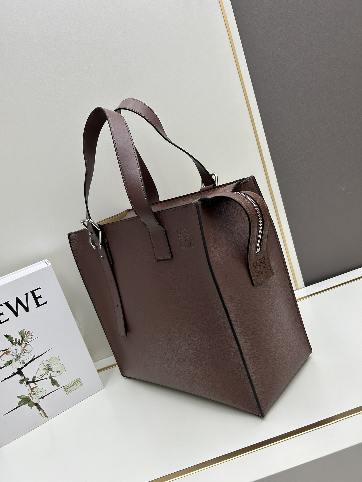 800 Loewe Buckle Tote手袋 新版本带拉链 
男仕托特包，型號3050A
宽大的容量和纤细的轮廓。扁平和不对称的双顶部手柄，饰有标志性的弧形开口搭扣，可通过链扣调节，适合不同的携带方式。主要特点：偏宽扁平矩形包身，内部拉链口袋，两个缝合插袋隔层，真皮里里，Anagram压印点缀 
尺寸36-33-17cm