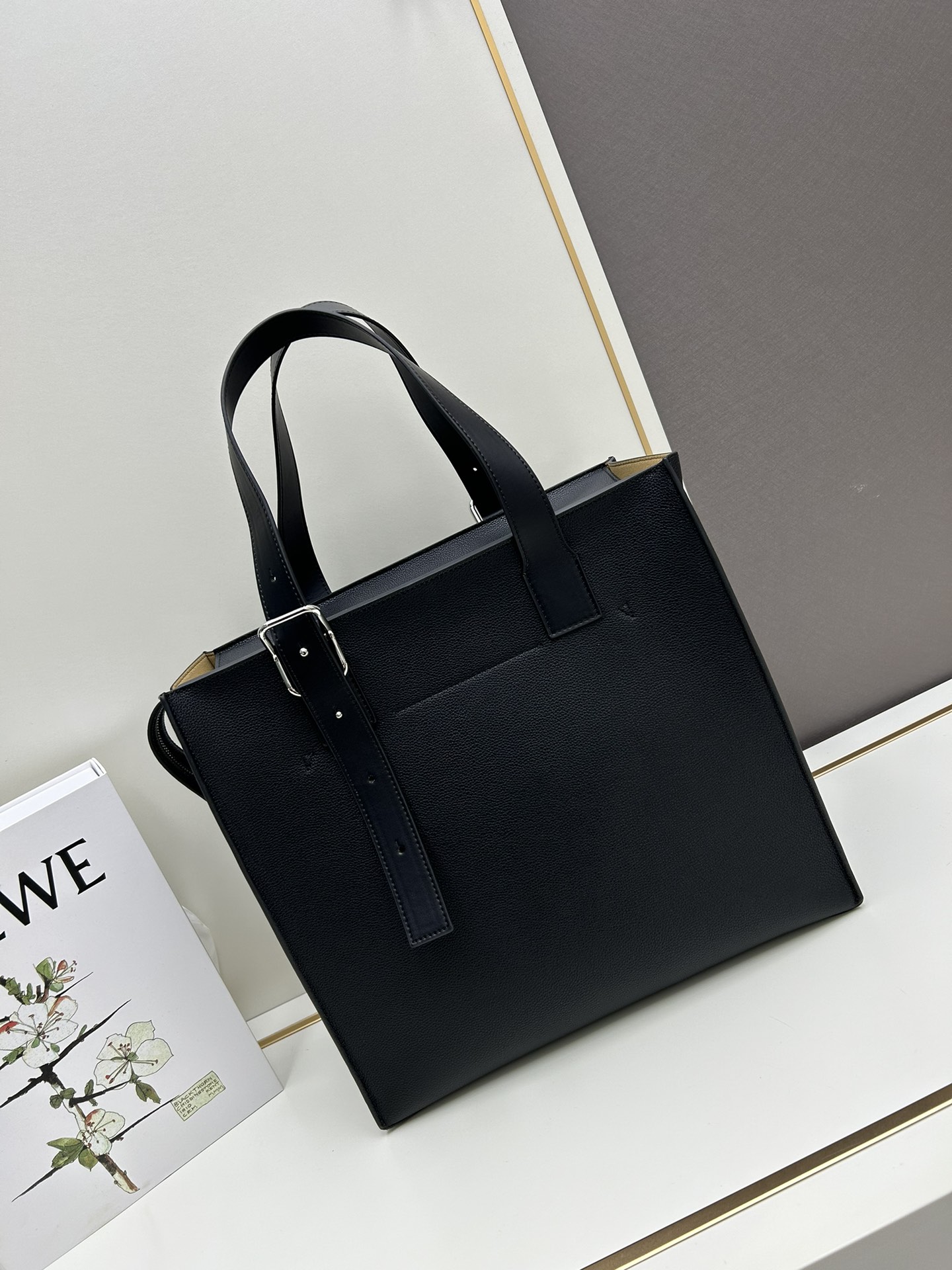 800 Loewe Buckle Tote手袋 新版本带拉链 
男仕托特包，型號3050A
宽大的容量和纤细的轮廓。扁平和不对称的双顶部手柄，饰有标志性的弧形开口搭扣，可通过链扣调节，适合不同的携带方式。主要特点：偏宽扁平矩形包身，内部拉链口袋，两个缝合插袋隔层，真皮里里，Anagram压印点缀 
尺寸36-33-17cm