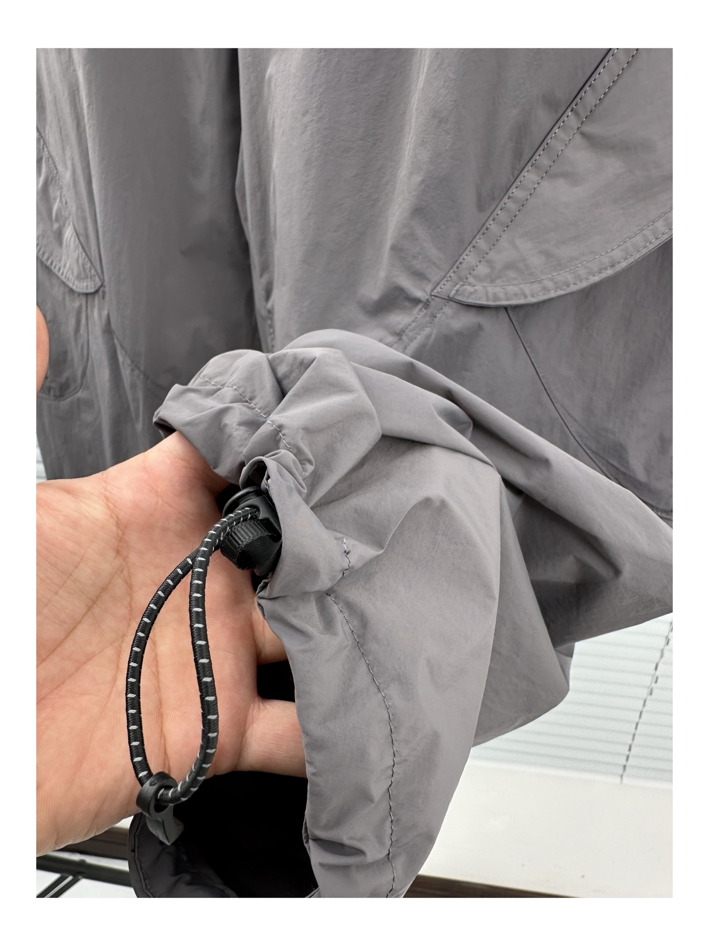 💰230 gw伞兵裤 灰色/黑色S-XL 
0系列 GW高端系列 弯刀立体伞兵口袋休闲裤25SS
设计特点
• 螺旋结构剪裁：采用独家“螺旋结构”立体剪裁，摒弃了传统裤子的侧缝和裆部切割，能完美贴合腿部动作，使行走更顺畅，活动自如。
• 多口袋设计：裤子设有翻盖及货运袋，沿切换线排列，有前、后、侧面等多个口袋，还有隐藏式安全口袋，增加视觉层次感的同时，方便实用，机能感十足。
• 3D建模腰部设计：配备3D设计的定制扣，调节按钮精致如雕塑，可轻松调节腰部，不仅实用，还增添了细节美感。
面料材质
• 防撕裂防水防风：选用双层软壳面料，具备适度的防风性能，外侧进行了无氟防水涂层处理，可有效抵御小雨，同时面料具有防撕裂功能，结实耐用。
• 环保舒适：面料中含有76%的再生聚酯，里侧触感柔软，亲肤舒适，兼具环保理念。
版型风格
• 阔腿版型：整体为阔腿设计，裤腿宽松，能够修饰腿型，对各种腿型都比较友好，穿着舒适自在，也增添了时尚感。
• 机能风：融合了功能性与时尚感，既适合户外活动，又能满足日常通勤穿搭需求，轻松打造机能风造型。

银灰色/黑色 S-XL
S 腰围78-86 臀围118 裤长100
M 腰围82-90 臀围122 裤长102
L 腰围86-94 臀围126 裤长103
XL 腰围90-98 臀围130 裤长105