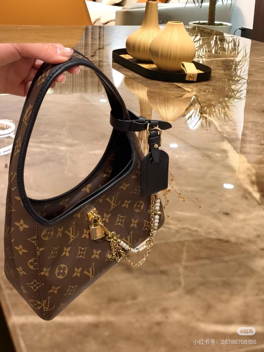 批160💰M12940老花黑色 手拎腋下包 当季新款 The Drop 小号手袋 本款 The Drop 小号手袋向 2018 年问世的 Flower Hobo 手袋汲取灵感，以经典 Monogram 帆布裁出兼具潮流格调与实用功能的雅致构型。标志性挂锁点缀名牌，与深邃皮革饰边共筑考究细节。可轻松收纳日常所需，契合都市生活节奏。15 x 12 x 28 厘米。