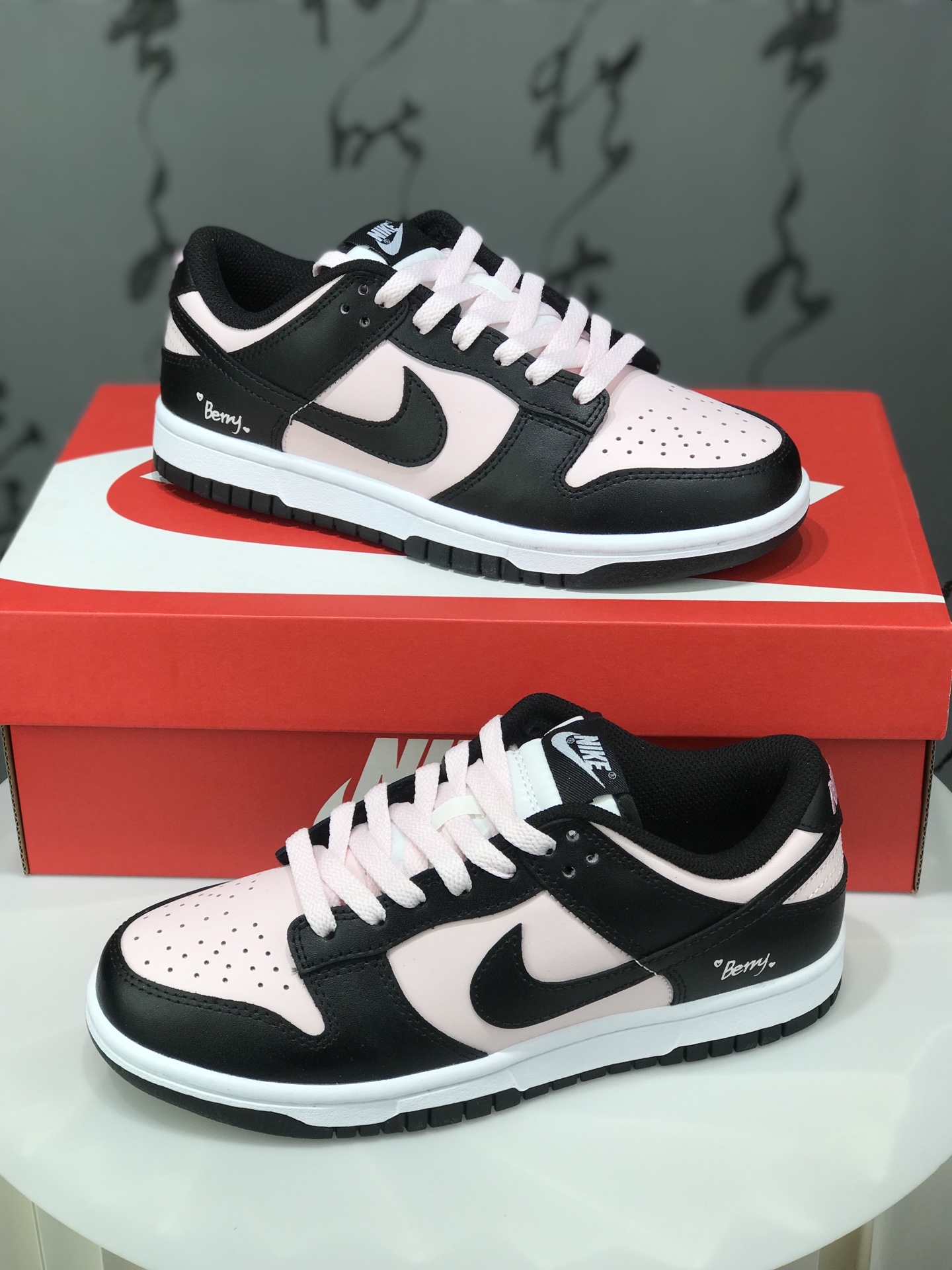 Nike Dunk Low 樱花白桃 黑粉 此款以春日樱花为灵感,将樱花的柔粉与白桃的清甜融入设计.鞋身以淡粉为主调,如初绽樱瓣细腻柔软;黑色Swoosh利落勾勒轮廓,甜碰撞出甜酷交织的视觉张力.后跟点缀手写风”Berry“与爱心细节,似一句俏皮密语,为整体设计注入灵动巧思. 货号:DD1391-100
