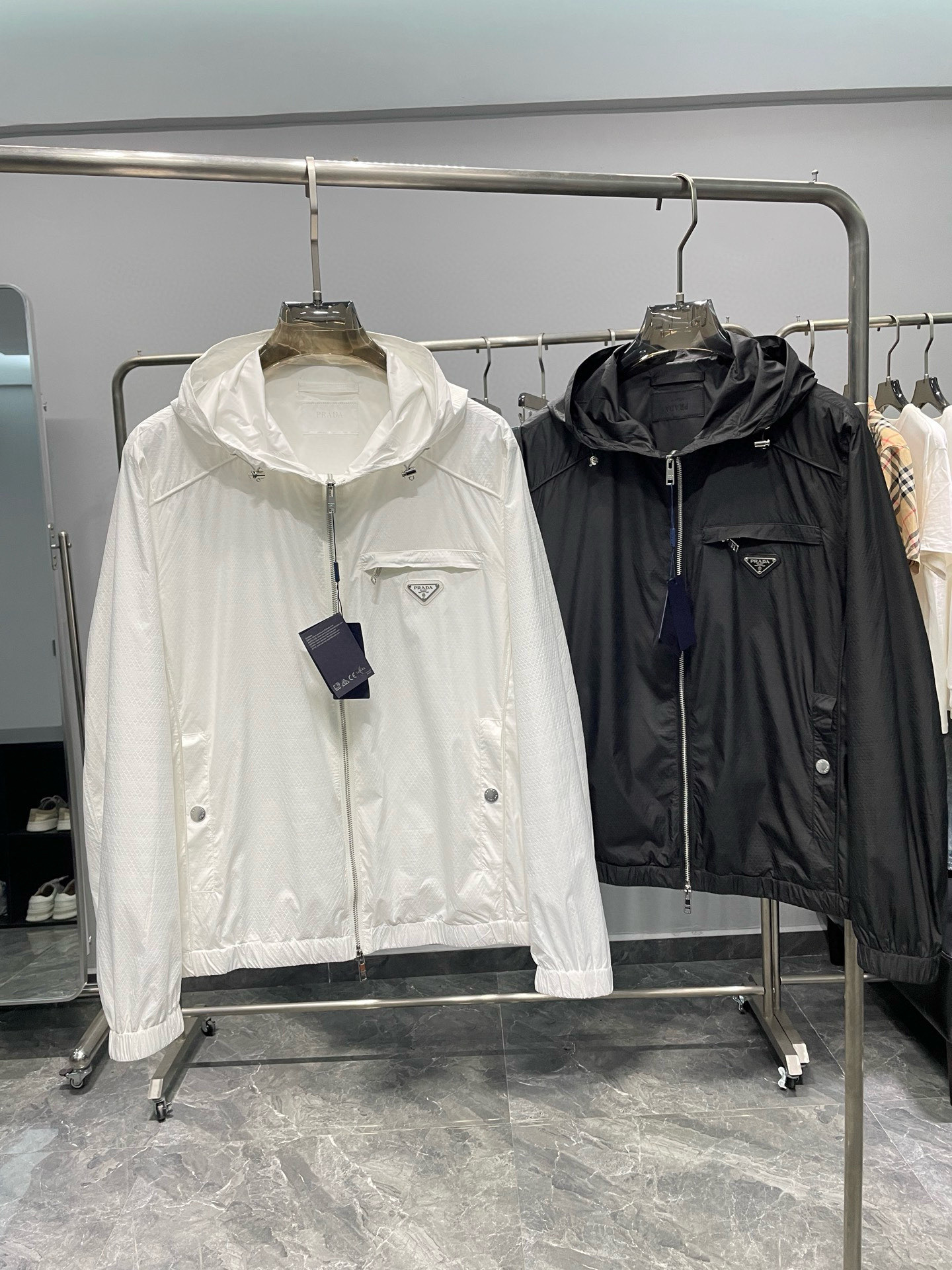 NO:135874,.Prada 25SS early spring new diamond plaid dark pattern fabric light and windproof jacket, men's triangle badge breast pocket outdoor casual zipper hooded jacket jacket!  Trading companies have sparse channels and are released on the official website at the same time!  In daily commuting or leisure time, the new PRA early spring windproof jacket is undoubtedly the first choice for versatility!  Whether paired with simple jeans and sneakers, or elegant suit pants and leather shoes, you can easily control various occasions and show the wearer's unique fashion charm!  The fabric is made of custom diamond lattice dark pattern technology fiber material. It is not only light in texture, but also comfortable like the second layer of skin, but also has excellent breathable and sweat-free performance. Even in the changing weather in spring and autumn or outdoor activities, you can keep your body dry and comfortable!  The delicate dark texture is clearly visible on the surface of the fabric. These textures are vaguely twinkle under the light, like the gentlest starlight in the night sky, adding a bit of high-end and restrained texture to the entire jacket!  The exquisite metal triangle badge stands quietly under the pocket on the chest. It is not only a symbol of the brand logo, but also exudes the unique tone of the brand!  And he also spared no effort in auxiliary materials. The customized brand engraved silver metal zippers are carefully polished, and the quality is unmatched. The zipper slides smoothly and every opening and closing reveals a calm elegance!  The drawstring hooded design not only increases the functionality of the clothing, but also gives the wearer more matching possibilities!  At the same time, the windproof beam design of the cuffs and hem effectively blocks the invasion of cold wind and ensures the warmth and comfort of the body!  Color white and black Size M-3XL Size reference M size shoulder width 46 bust 112 sleeve length 64 clothes length 66 L size shoulder width 47 bust 116 sleeve length 65 clothes length 67 XL size shoulder width 48 bust 120 sleeve length 66 clothes length 68 2XL size shoulder width 49 bust 124 sleeve length 67 clothes length 69 3XL size shoulder width 50 bust 128 sleeve length 68 clothes length 70, prada, prada, sneakers, jeans, jackets & coats, jackets & coats, business suit, hats, alexander wang19860909.普拉达 25SS早春新款菱形格暗纹面料轻薄防风夹克,男士三角标徽章胸袋户外休闲拉链连帽夹克外套！贸易公司渠道稀出,同步官网发售！在日常通勤或休闲时光里,PRA早春新款防风夹克无疑是百搭的首选！无论是搭配简约的牛仔裤与运动鞋,还是优雅的西装裤与皮鞋,都能轻松驾驭各种场合,展现出穿着者独特的时尚魅力！ 其面料选用了客供定制的菱形格暗纹科技纤维材质,不仅质地轻盈,如同第二层肌肤般贴合舒适,更具备了卓越的透气排汗性能,即便是在春秋多变的天气或是户外活动中,也能保持身体的干爽与自在！面料表面清晰可见细腻的暗纹肌理,这些纹理在光线的照耀下隐约闪烁,仿佛夜空中最温柔的星光,为整件夹克增添了几分高级而内敛的质感！ 胸前口袋下方精致的金属三角标徽章静静伫立,它不仅是品牌标识的象征,更散发着品牌独有的调性！而在辅料方面同样不遗余力.客供定制的品牌刻印银色金属拉链,每一齿都经过精心打磨,品相无法挑剔,拉链的滑动顺畅无阻,每一次开合都透露出一种从容不迫的优雅！抽绳式连帽设计不仅增加了服装的功能性,更赋予了穿着者更多的搭配可能！同时袖口及下摆的防风束口设计,有效阻挡了冷风侵袭,确保了身体的温暖与舒适！ 颜色白色、黑色 尺码M-3XL 尺寸参考 M码肩宽46胸围112袖长64衣长66 L码肩宽47胸围116袖长65衣长67 XL码肩宽48胸围120袖长66衣长68 2XL码肩宽49胸围124袖长67衣长69 3XL码肩宽50胸围128袖长68衣长70,,prada,prada,sneakers,jeans,jackets & coats,jackets & coats,business suit,hats,alexander wang,Men's clothing