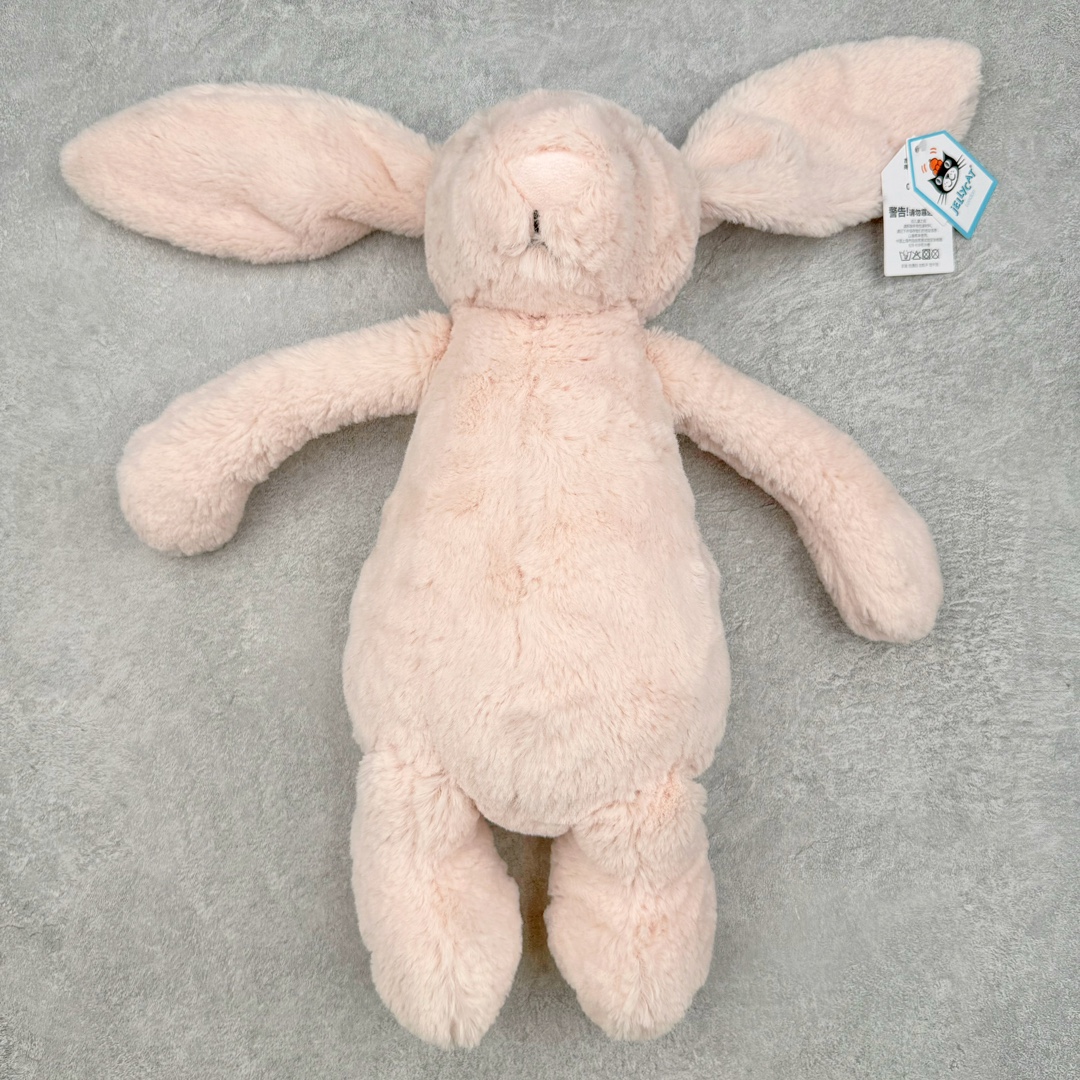 ＃原单 Jellycat 玩偶 毛绒公仔 邦尼兔 31CM 科普：Jellycat是一个英国玩具品牌，创立于1999年，由William和Thomas兄弟二人在伦敦创立。该品牌专注于设计玩偶玩具，并全情投入于最有趣、环保和独特的软玩具领域。Jellycat的产品设计丰富且有创意，其毛绒玩具以可爱的动物形象为主打，深受全球儿童的喜爱。品牌的产品线包括各种动物系列、海洋系列、蔬果美食系列、植物系列等，每个系列都有其独特的设计和故事。Jellycat的产品设计理念是打破传统动物毛绒像动物标本一样的形象，通过改变形状、手感、颜色、大小和材料，用成千上万种方式制作一只动物毛绒。品牌的设计师来自世界各地，他们的创意让产品更具多元性，同时也让品牌能够从世界各地的文化中获得设计灵感。近年来，Jellycat品牌方开始跨界合作，与野兽派、华尔道夫酒店等品牌合作推出联名产品，进一步扩大了品牌的影响力。在社交媒体上，Jellycat也日益活跃，通过小红书、Instagram、抖音和TikTok等平台与消费者互动，分享品牌故事和产品信息。Jellycat的产品价格在99元到1699元不等，绝版产品的价格在二手平台上甚至会翻几倍。尽管有消费者认为它高价低质，价格贵、品控不严格等问题频频引来吐槽，但仍有大量粉丝愿意为“治愈”买单，因为这些毛绒玩具成为他们精神上的陪伴。原装100% polyester进口聚酯纤维面料 原厂7D棉 原单环保颗粒 双吊牌加三重水洗标 原配防尘袋 吊打市面通货 注意即使同一家厂 不同的批次面料缸差是一定都有的 官网不同批次都有 经过欧盟CE安全认证 此标准0-100岁的小朋友都适用 这个缸差和造型其实经常入手玩偶的都知道 手工制品 世上每一只jell 都是独一无二的 轻微线头 轻微不对称都是很正常的 无法避免 官网都是一样 底部走线 颗粒填充物 刺绣 走线 肉眼可见的精致 原色未染色面料纱线 超级有质感-选品中心