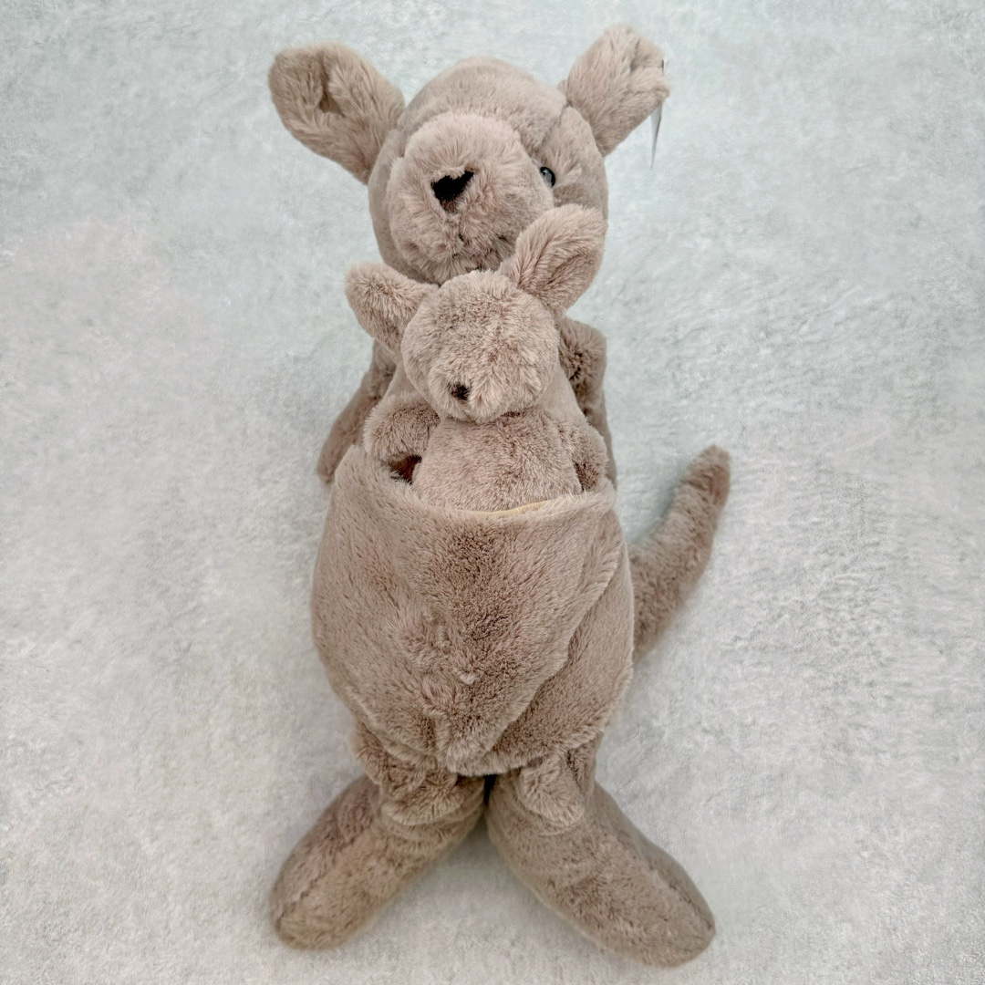 ＃原单 Jellycat 玩偶 毛绒公仔 卡娜袋鼠 37CM 科普：Jellycat是一个英国玩具品牌，创立于1999年，由William和Thomas兄弟二人在伦敦创立。该品牌专注于设计玩偶玩具，并全情投入于最有趣、环保和独特的软玩具领域。Jellycat的产品设计丰富且有创意，其毛绒玩具以可爱的动物形象为主打，深受全球儿童的喜爱。品牌的产品线包括各种动物系列、海洋系列、蔬果美食系列、植物系列等，每个系列都有其独特的设计和故事。Jellycat的产品设计理念是打破传统动物毛绒像动物标本一样的形象，通过改变形状、手感、颜色、大小和材料，用成千上万种方式制作一只动物毛绒。品牌的设计师来自世界各地，他们的创意让产品更具多元性，同时也让品牌能够从世界各地的文化中获得设计灵感。近年来，Jellycat品牌方开始跨界合作，与野兽派、华尔道夫酒店等品牌合作推出联名产品，进一步扩大了品牌的影响力。在社交媒体上，Jellycat也日益活跃，通过小红书、Instagram、抖音和TikTok等平台与消费者互动，分享品牌故事和产品信息。Jellycat的产品价格在99元到1699元不等，绝版产品的价格在二手平台上甚至会翻几倍。尽管有消费者认为它高价低质，价格贵、品控不严格等问题频频引来吐槽，但仍有大量粉丝愿意为“治愈”买单，因为这些毛绒玩具成为他们精神上的陪伴。原装100% polyester进口聚酯纤维面料 原厂7D棉 原单环保颗粒 双吊牌加三重水洗标 原配防尘袋 吊打市面通货 注意即使同一家厂 不同的批次面料缸差是一定都有的 官网不同批次都有 经过欧盟CE安全认证 此标准0-100岁的小朋友都适用 这个缸差和造型其实经常入手玩偶的都知道 手工制品 世上每一只jell 都是独一无二的 轻微线头 轻微不对称都是很正常的 无法避免 官网都是一样 底部走线 颗粒填充物 刺绣 走线 肉眼可见的精致 原色未染色面料纱线 超级有质感-选品中心