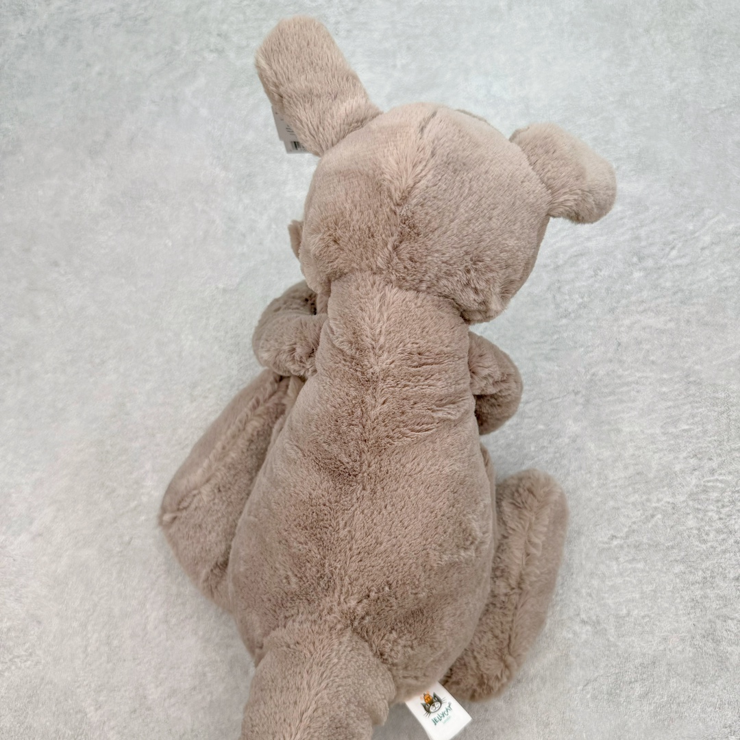 图片[4]-＃原单 Jellycat 玩偶 毛绒公仔 卡娜袋鼠 37CM 科普：Jellycat是一个英国玩具品牌，创立于1999年，由William和Thomas兄弟二人在伦敦创立。该品牌专注于设计玩偶玩具，并全情投入于最有趣、环保和独特的软玩具领域。Jellycat的产品设计丰富且有创意，其毛绒玩具以可爱的动物形象为主打，深受全球儿童的喜爱。品牌的产品线包括各种动物系列、海洋系列、蔬果美食系列、植物系列等，每个系列都有其独特的设计和故事。Jellycat的产品设计理念是打破传统动物毛绒像动物标本一样的形象，通过改变形状、手感、颜色、大小和材料，用成千上万种方式制作一只动物毛绒。品牌的设计师来自世界各地，他们的创意让产品更具多元性，同时也让品牌能够从世界各地的文化中获得设计灵感。近年来，Jellycat品牌方开始跨界合作，与野兽派、华尔道夫酒店等品牌合作推出联名产品，进一步扩大了品牌的影响力。在社交媒体上，Jellycat也日益活跃，通过小红书、Instagram、抖音和TikTok等平台与消费者互动，分享品牌故事和产品信息。Jellycat的产品价格在99元到1699元不等，绝版产品的价格在二手平台上甚至会翻几倍。尽管有消费者认为它高价低质，价格贵、品控不严格等问题频频引来吐槽，但仍有大量粉丝愿意为“治愈”买单，因为这些毛绒玩具成为他们精神上的陪伴。原装100% polyester进口聚酯纤维面料 原厂7D棉 原单环保颗粒 双吊牌加三重水洗标 原配防尘袋 吊打市面通货 注意即使同一家厂 不同的批次面料缸差是一定都有的 官网不同批次都有 经过欧盟CE安全认证 此标准0-100岁的小朋友都适用 这个缸差和造型其实经常入手玩偶的都知道 手工制品 世上每一只jell 都是独一无二的 轻微线头 轻微不对称都是很正常的 无法避免 官网都是一样 底部走线 颗粒填充物 刺绣 走线 肉眼可见的精致 原色未染色面料纱线 超级有质感-选品中心