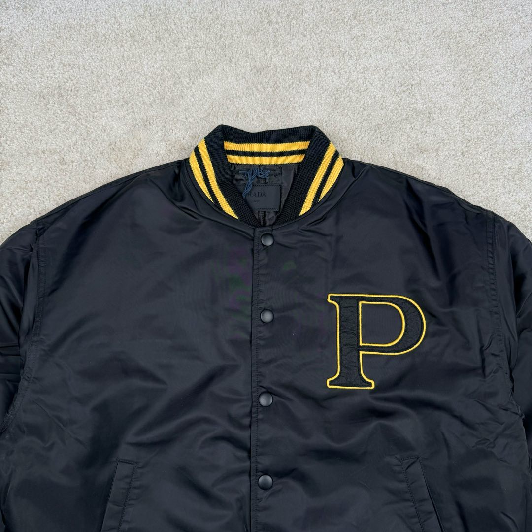 图片[4]-＃GD广顶 PRADA FW24 普拉达字母印花条纹单排扣飞行员夹克外套 黑色 官网价：19300￥（1908C）采用【100%锦纶斜纹面料】【厚度75D】底面做过胶增加面料手感挺度 采用【200D无妨底布】【激光烧花切割章仔】外围采用【国产高速机】【涤纶材质丝光线包边刺绣】开章仔模版【手摇绣花机贴裁片章仔】采用【人造丝斜纹缎面里布】【2寸双针间1200#洗水棉横条】螺纹采用【ADF加长机】织造【10s精梳棉色纱+2根氨纶高丝】-选品中心