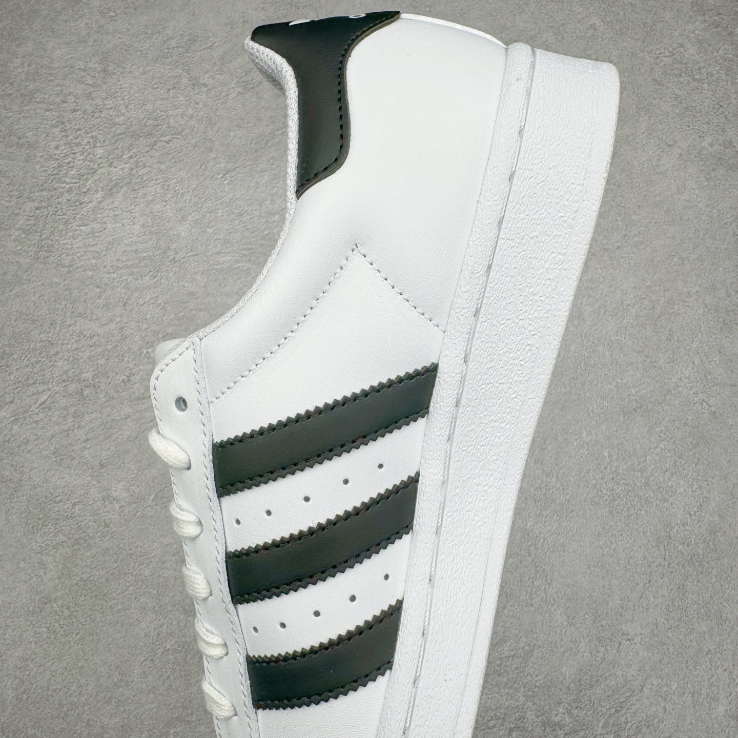 图片[7]-＃G版 AD Originals Superstar 经典贝壳头休闲板鞋 白黑 EG4958 市面最完美的贝壳头版型 2024全新细节 注意区分旧版 随意对比市面 知名大厂出品 正常个位数利润的单价 百分百全新货品 零氧化发霉 给足利润空间操作 独家控货 平台正单 全套原纸板楦头开发 每道工序同步公司流程 确保原汁原味 完美呈现原鞋版型 原厂高频磨具加持 精准内部资源对接 Logo字体百分百还原 全鞋电脑针车 Logo针车间距针数原版一致 皮料切割冲裁零瑕疵 原鞋一致含胶量超耐磨大底 大几率过验 不对比市面只对比原鞋 只服务最高端市场 诞生于1969年 是第一双将全皮面鞋 身与橡胶鞋头结合在一起的低帮篮球鞋 Superstar最开始 是作为高帮篮球鞋Pro Model的低帮版本而出现的 但因为其独特和醒目的橡胶鞋头造型而让大家熟知 被大家形象地称为\\\”shelltoe\\\”贝壳头 在70年代的美国职业篮球场上 接近3/4的NBA球员都将这双Superstar作为场上用鞋 80年代之后 经过不断的改良和发展 Superstar逐渐成为横跨时装、音乐、街头文化、休闲和运动等各大领域的时尚潮鞋 尺码：35.5 36 36.5 37 38 38.5 39 40 40.5 41 42 42.5 43 44 44.5 45 46-选品中心