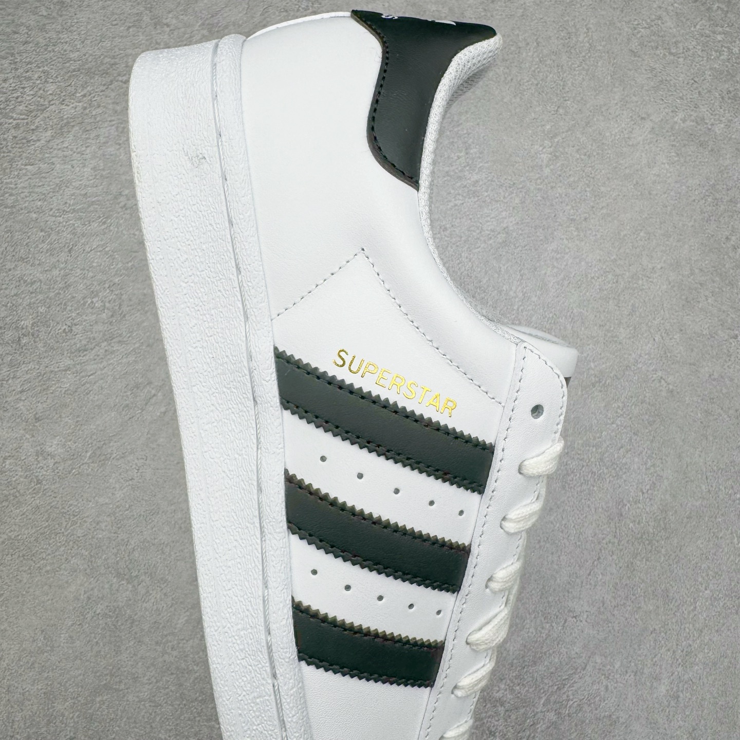 图片[6]-＃G版 AD Originals Superstar 经典贝壳头休闲板鞋 白黑 EG4958 市面最完美的贝壳头版型 2024全新细节 注意区分旧版 随意对比市面 知名大厂出品 正常个位数利润的单价 百分百全新货品 零氧化发霉 给足利润空间操作 独家控货 平台正单 全套原纸板楦头开发 每道工序同步公司流程 确保原汁原味 完美呈现原鞋版型 原厂高频磨具加持 精准内部资源对接 Logo字体百分百还原 全鞋电脑针车 Logo针车间距针数原版一致 皮料切割冲裁零瑕疵 原鞋一致含胶量超耐磨大底 大几率过验 不对比市面只对比原鞋 只服务最高端市场 诞生于1969年 是第一双将全皮面鞋 身与橡胶鞋头结合在一起的低帮篮球鞋 Superstar最开始 是作为高帮篮球鞋Pro Model的低帮版本而出现的 但因为其独特和醒目的橡胶鞋头造型而让大家熟知 被大家形象地称为\\\”shelltoe\\\”贝壳头 在70年代的美国职业篮球场上 接近3/4的NBA球员都将这双Superstar作为场上用鞋 80年代之后 经过不断的改良和发展 Superstar逐渐成为横跨时装、音乐、街头文化、休闲和运动等各大领域的时尚潮鞋 尺码：35.5 36 36.5 37 38 38.5 39 40 40.5 41 42 42.5 43 44 44.5 45 46-选品中心