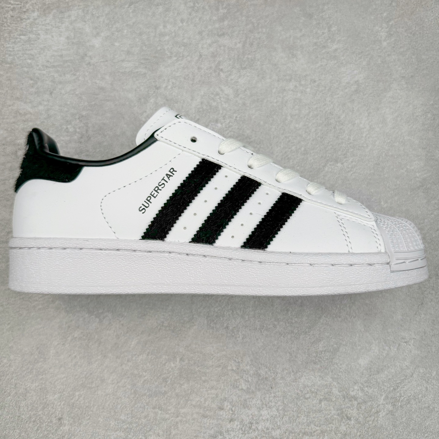 AD Originals Superstar 经典复古贝壳头板鞋 JH7052 诞生于1969年 是第一双将全皮面鞋 身与橡胶鞋头结合在一起的低帮篮球鞋 Superstar最开始 是作为高帮篮球鞋Pro Model的低帮版本而出现的 但因为其独特和醒目的橡胶鞋头造型而让大家熟知 被大家形象地称为\\\